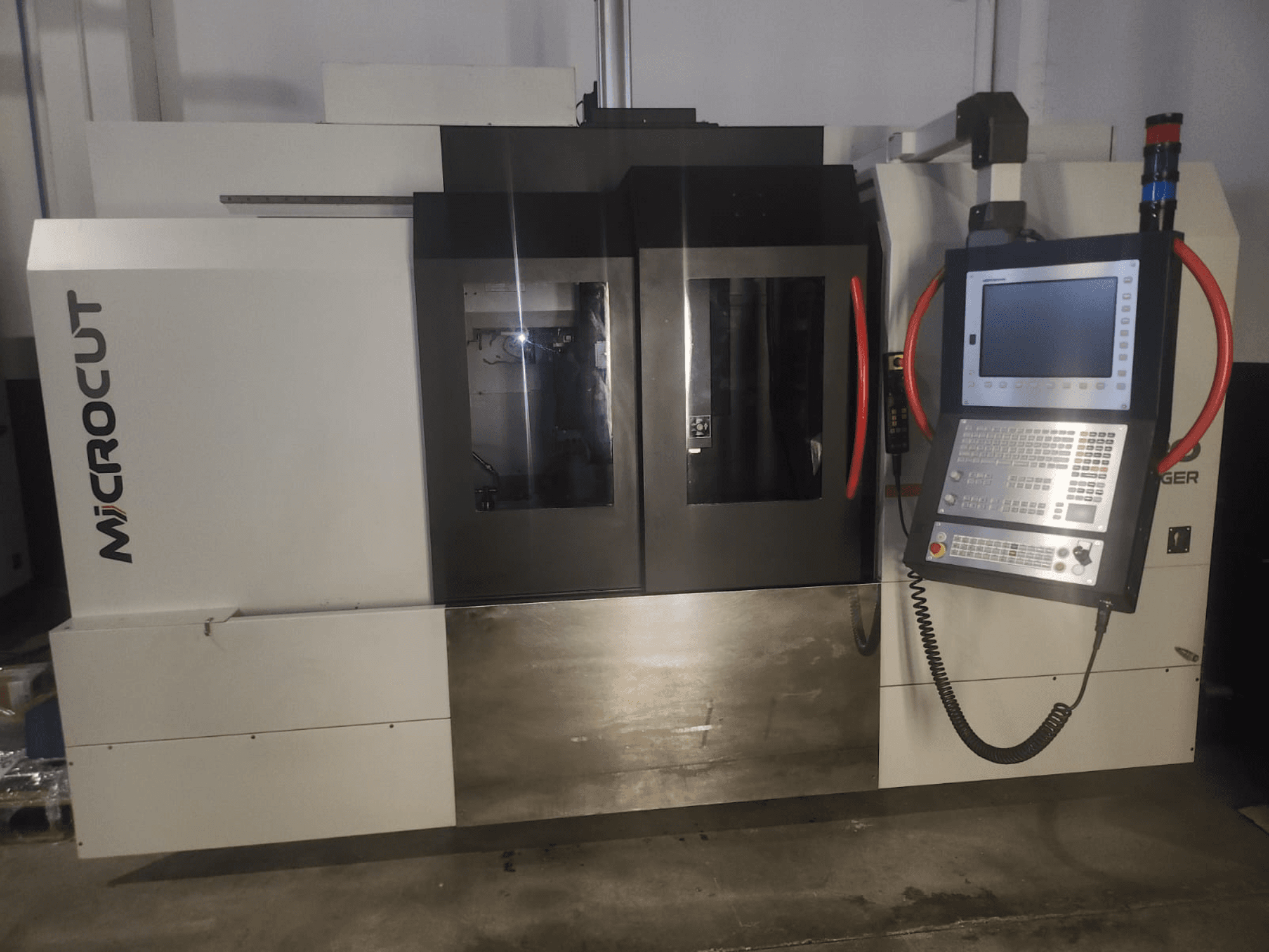 Microcut CNC makinesinin önden görünümü; kontrol paneli, çift pencere, endüstriyel tasarım ve metalik kaplama özelliklerine sahiptir.