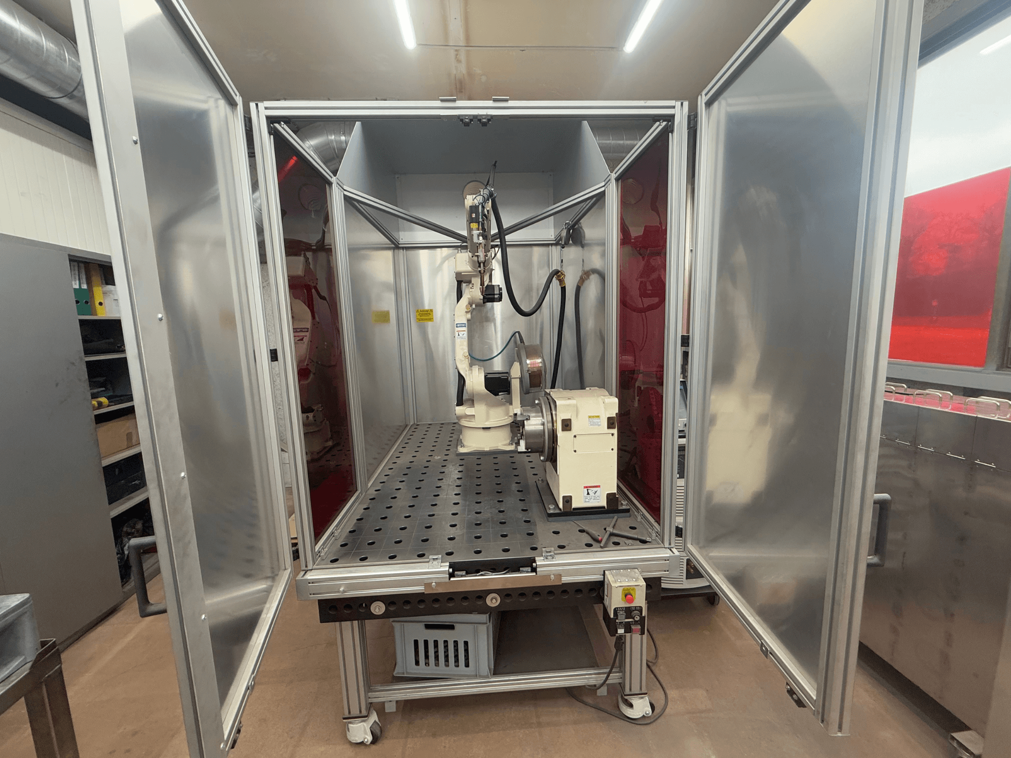 Kaynak robotu OTC Daihen EASY ARC V02.04 metal bir muhafaza içinde, önden bakıldığında mafsallı kolunu ve kontrol panelini sergiliyor.
