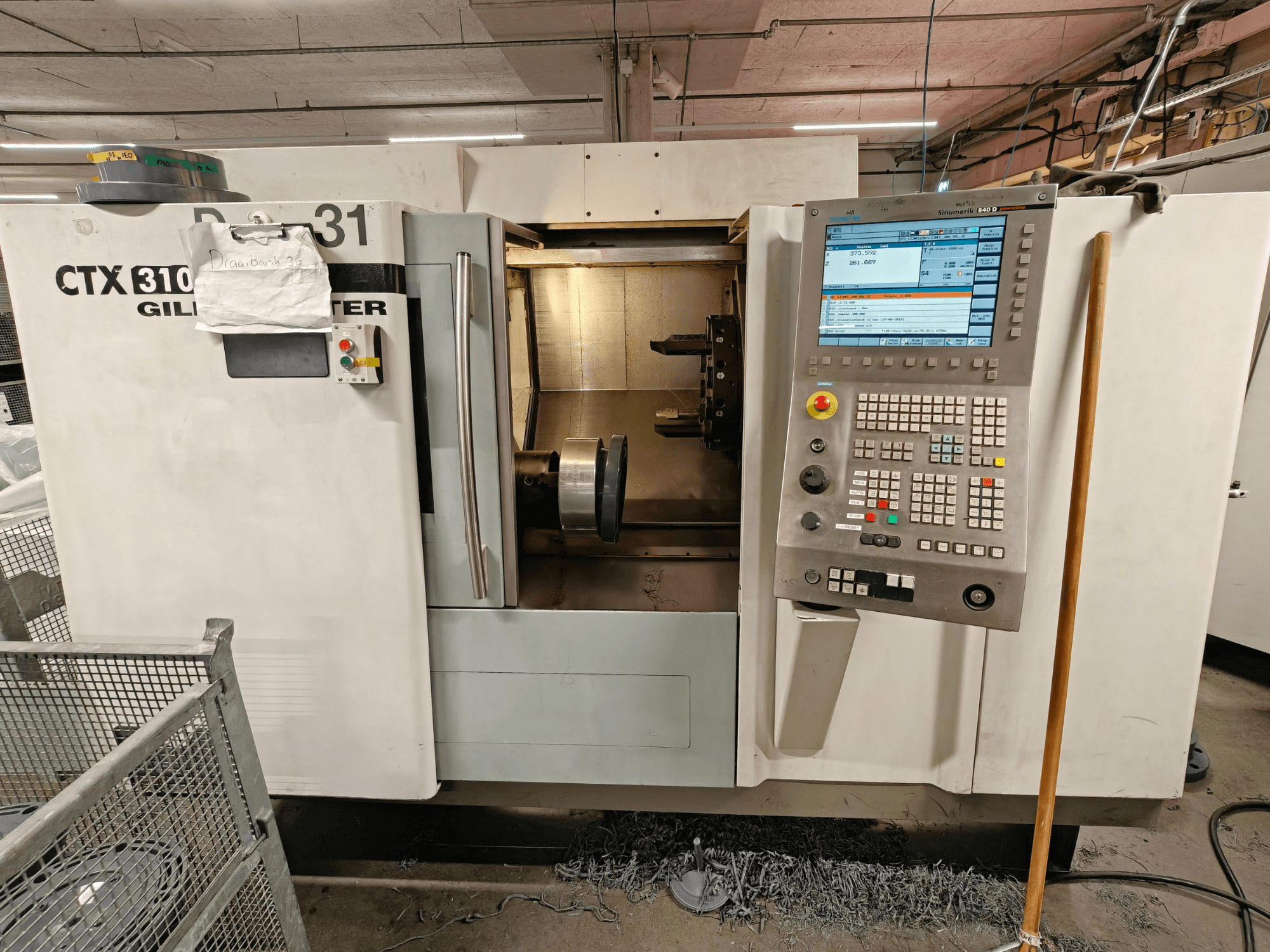 Gildemeister CTX 310 yatay torna makinesi, kontrol paneli ile önden görünüm, içerideki aletleri ve çalışma alanını gösterir.
