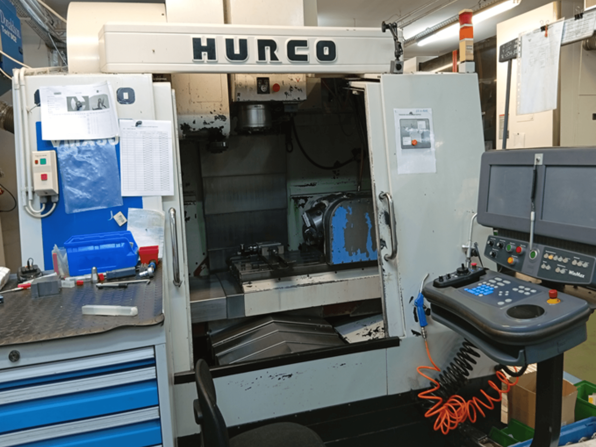 Hurco VMX 30T dikey işleme merkezi, önden görünüm, kontrol panelini, çalışma alanını ve kısmen açık kapıyı gösterir.