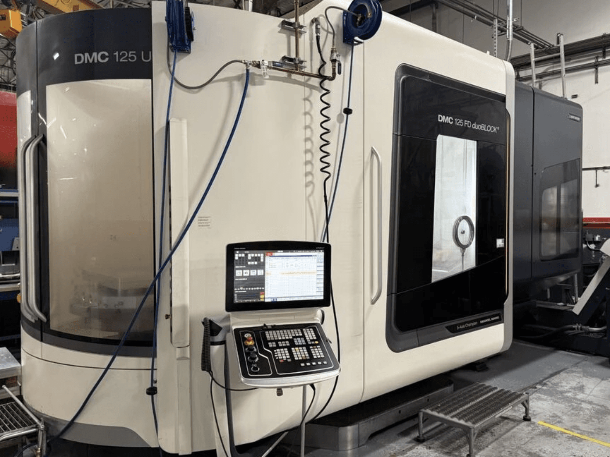 DMG MORI DMC 125 U duoBLOCK evrensel işleme merkezi, kontrol paneli ve yansıtıcı yüzeylerin bulunduğu önden görünüm.