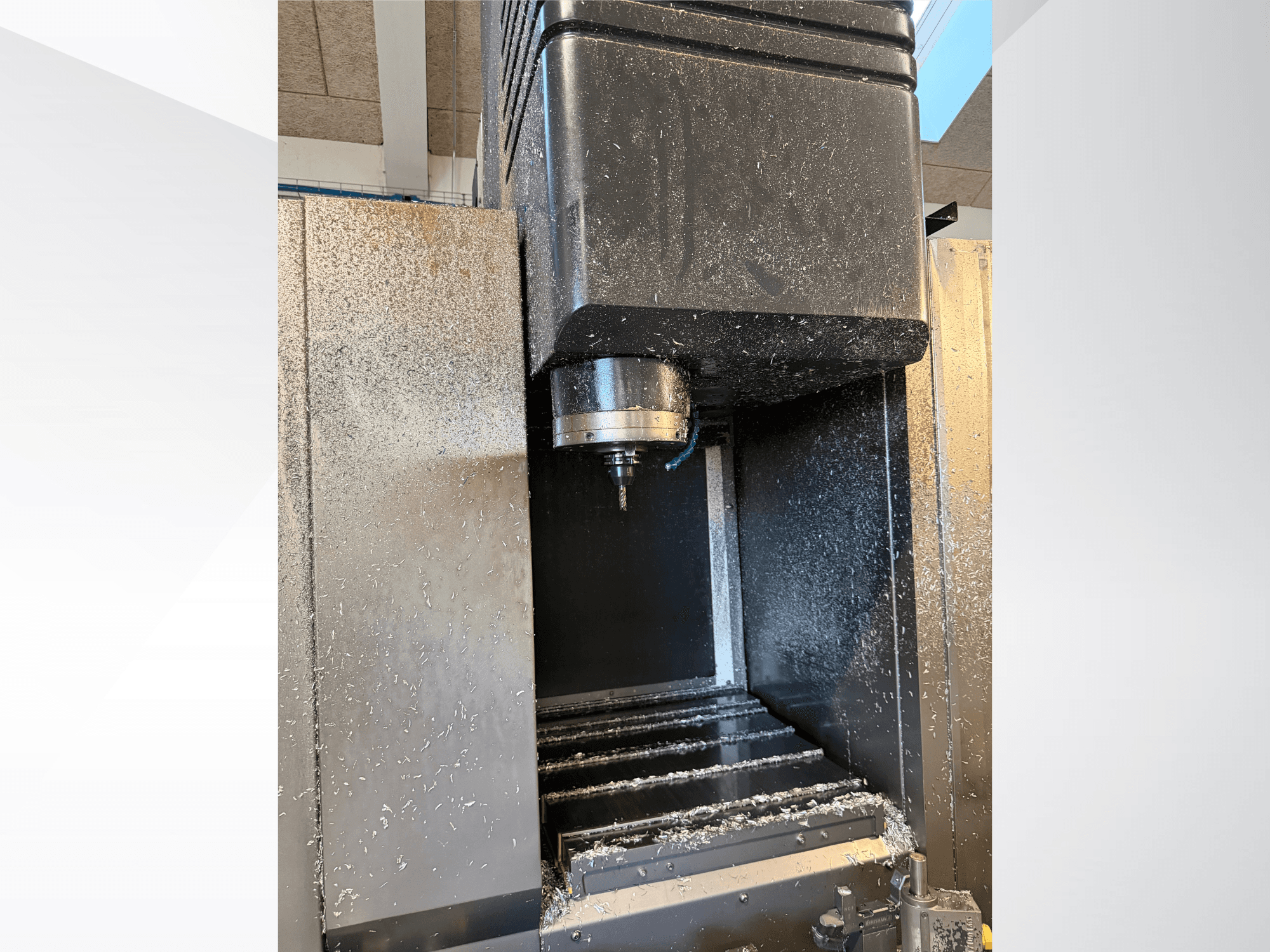 Mazak VTC 300C II dikey işleme merkezi, önden görünüm; işleme sürecinden kaynaklanan iş mili ve talaşlar görülmektedir.