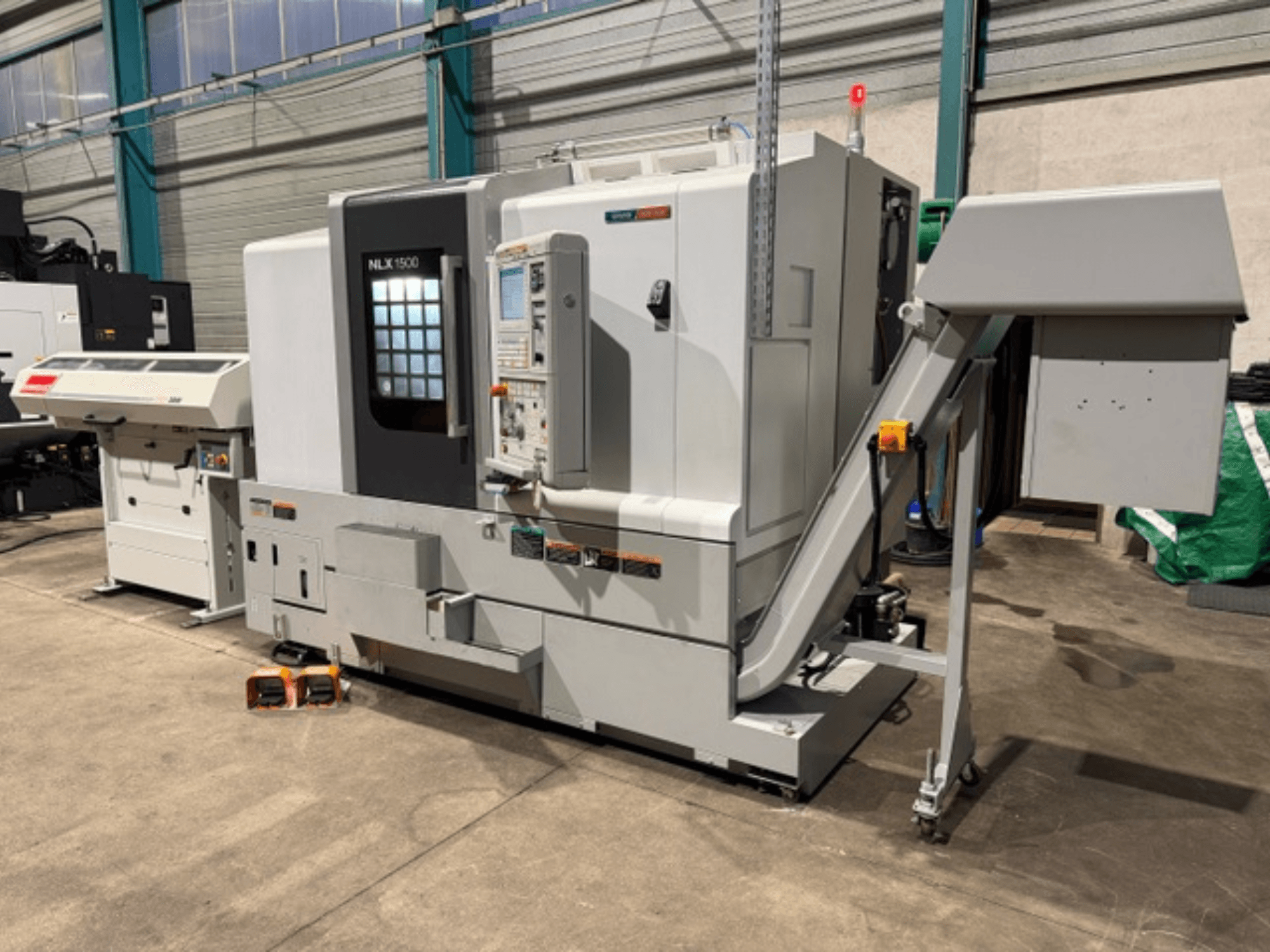 NLK 1500 CNC makinesi, önden görünüm, kontrol paneli ve aksesuar haznesi yanda, beton zemin üzerinde.
