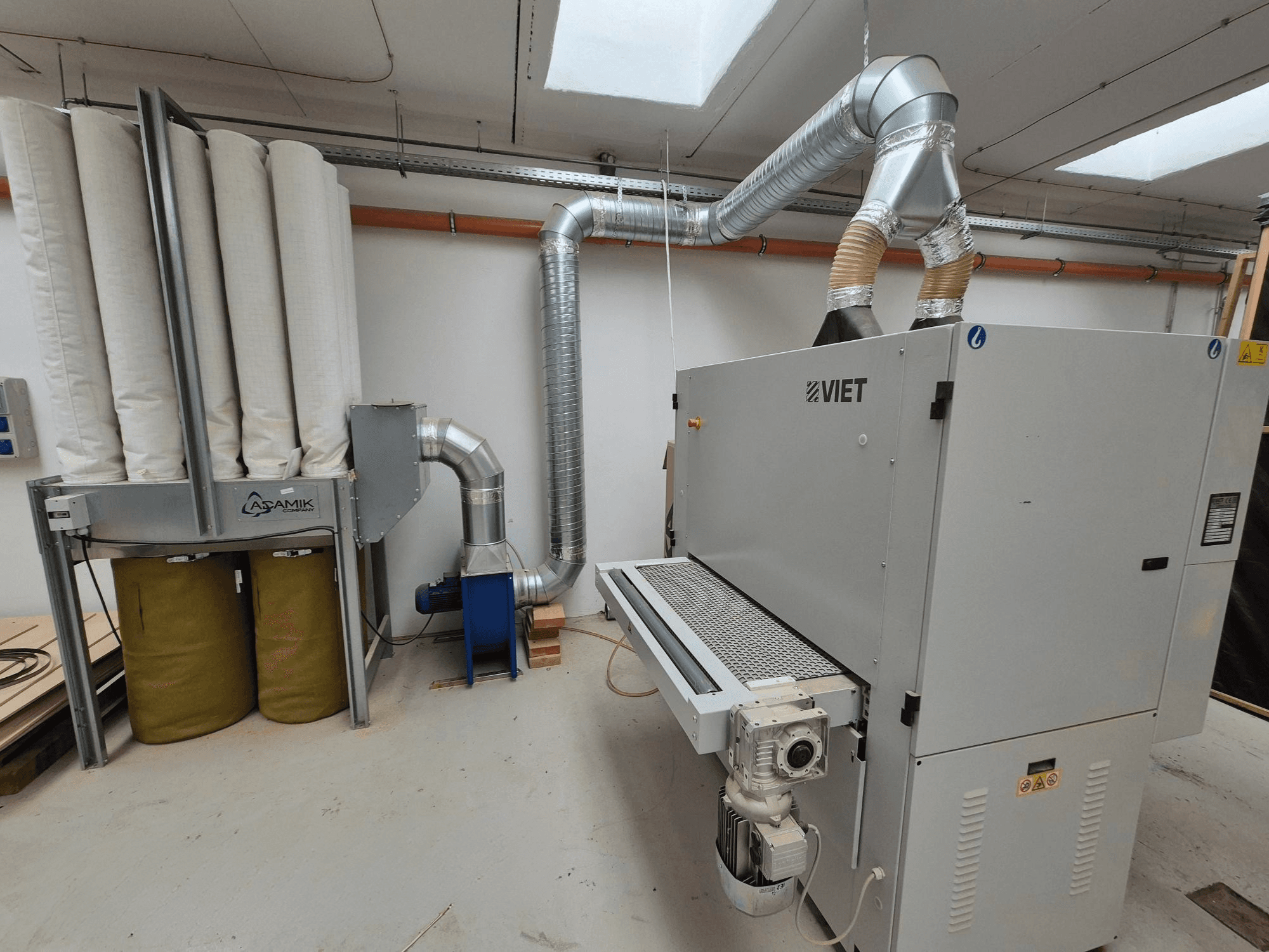 Silindirik filtrelere ve gümüş renkli egzoza sahip Viet toz emme sistemi, atölye ortamında önden görünüm.