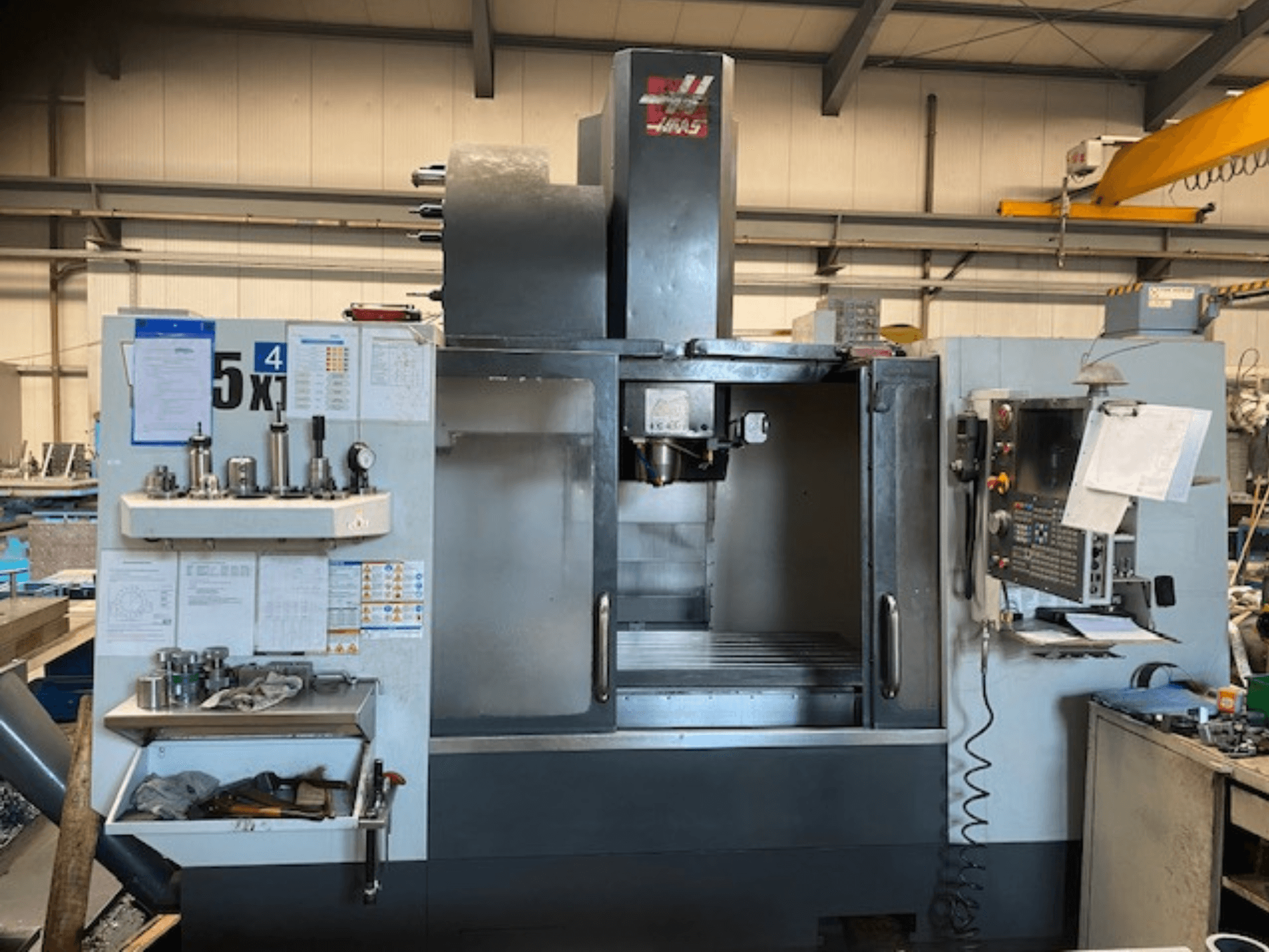 Haas VF-5 dikey işleme merkezi, önden görünüm, kontrol paneli, takım depolama ve iş mili alanı.