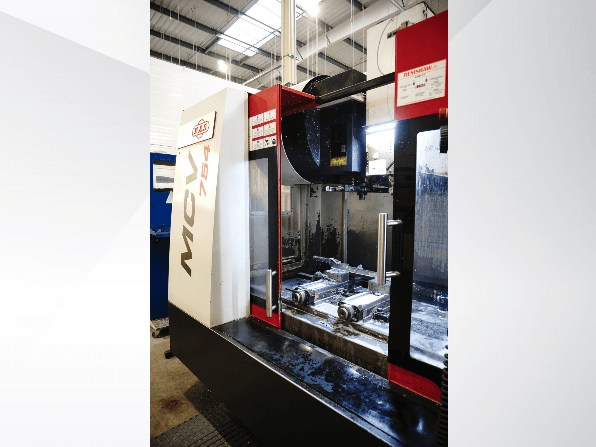 TAKUMI MCV 754 CNC freze makinesi, önden görünüm, bir atölye ortamında metal talaşları ve hassas takımları sergiliyor.