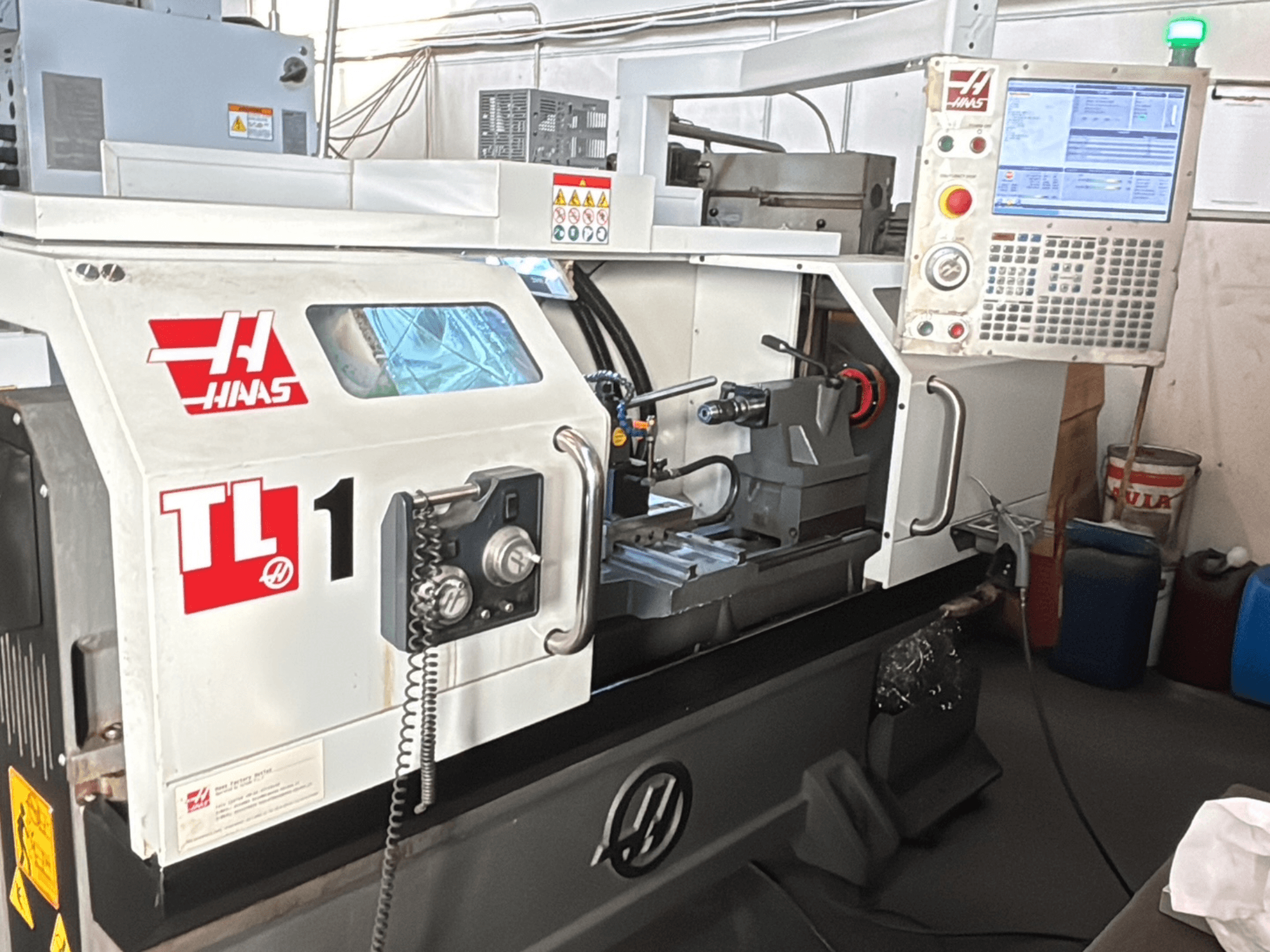 Haas TL-1 CNC torna makinesi, önden görünüm, ekranlı kontrol paneli, takım tutucu ve güvenlik etiketleri.