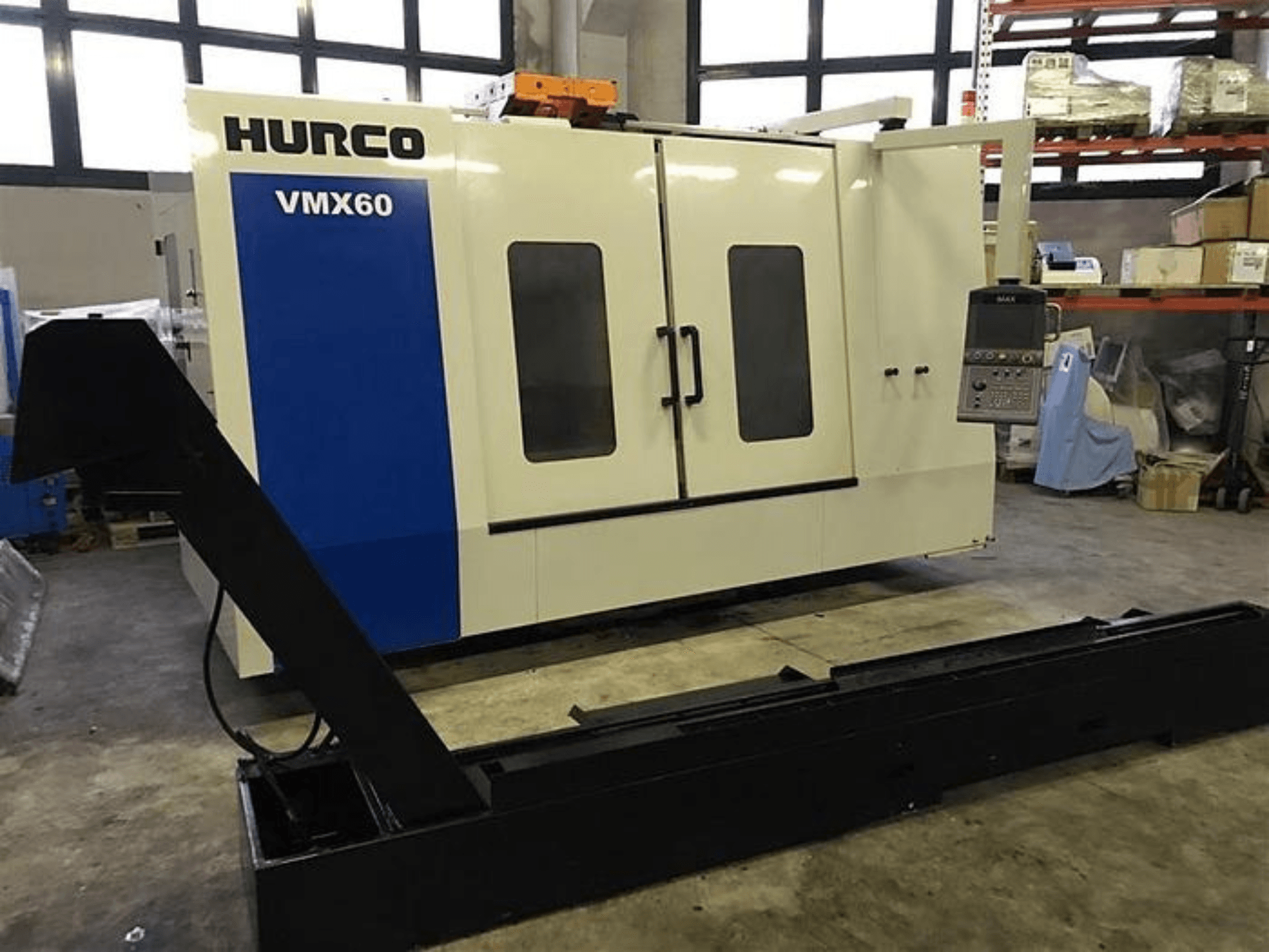 Bir atölyedeki HURCO VMX60 CNC makinesi, önden görünüm, kontrol paneli ve bağlı siyah destek rayı.