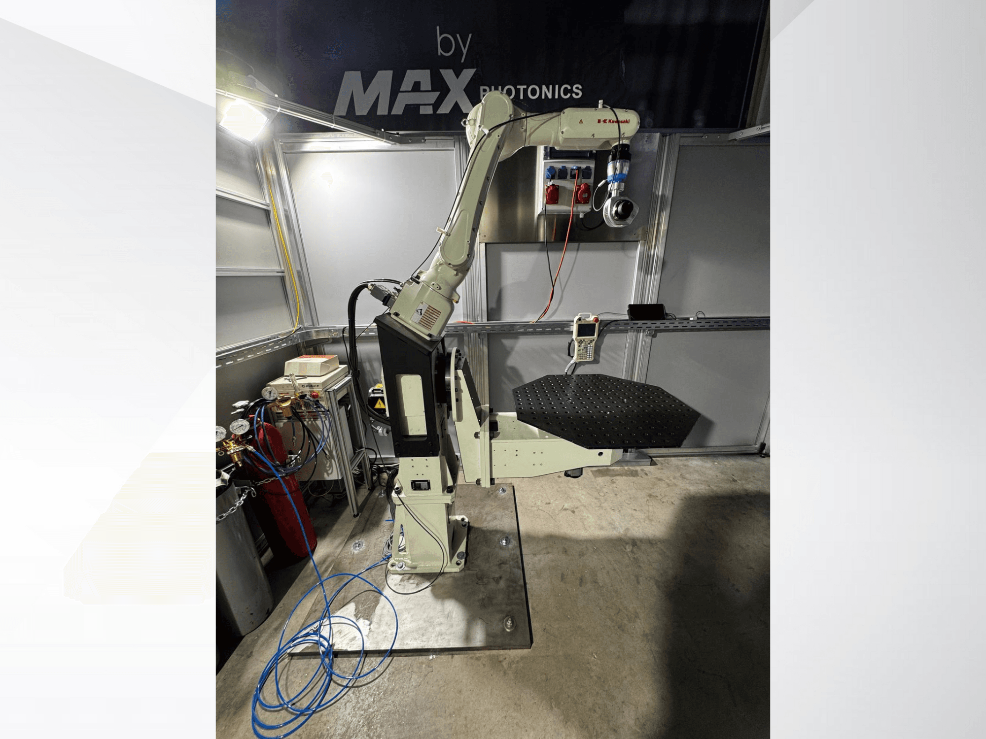 Max Photonics robotik kol aparatı, önden görünüm, siyah delikli bir platform ve göstergeler ve kablolar içeren kontrol paneli.