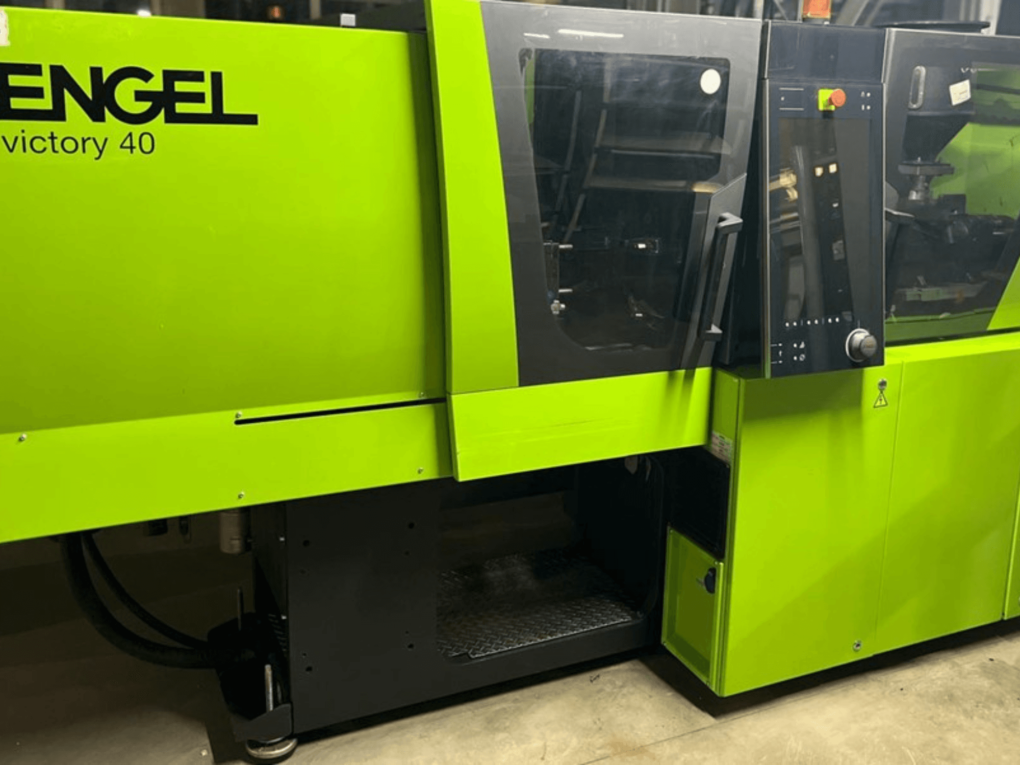 ENGEL Victory 40 parlak yeşil renkli plastik enjeksiyon makinesi, kontrol panelini ve uyarı etiketli erişim kapısını gösteren önden görünüm.