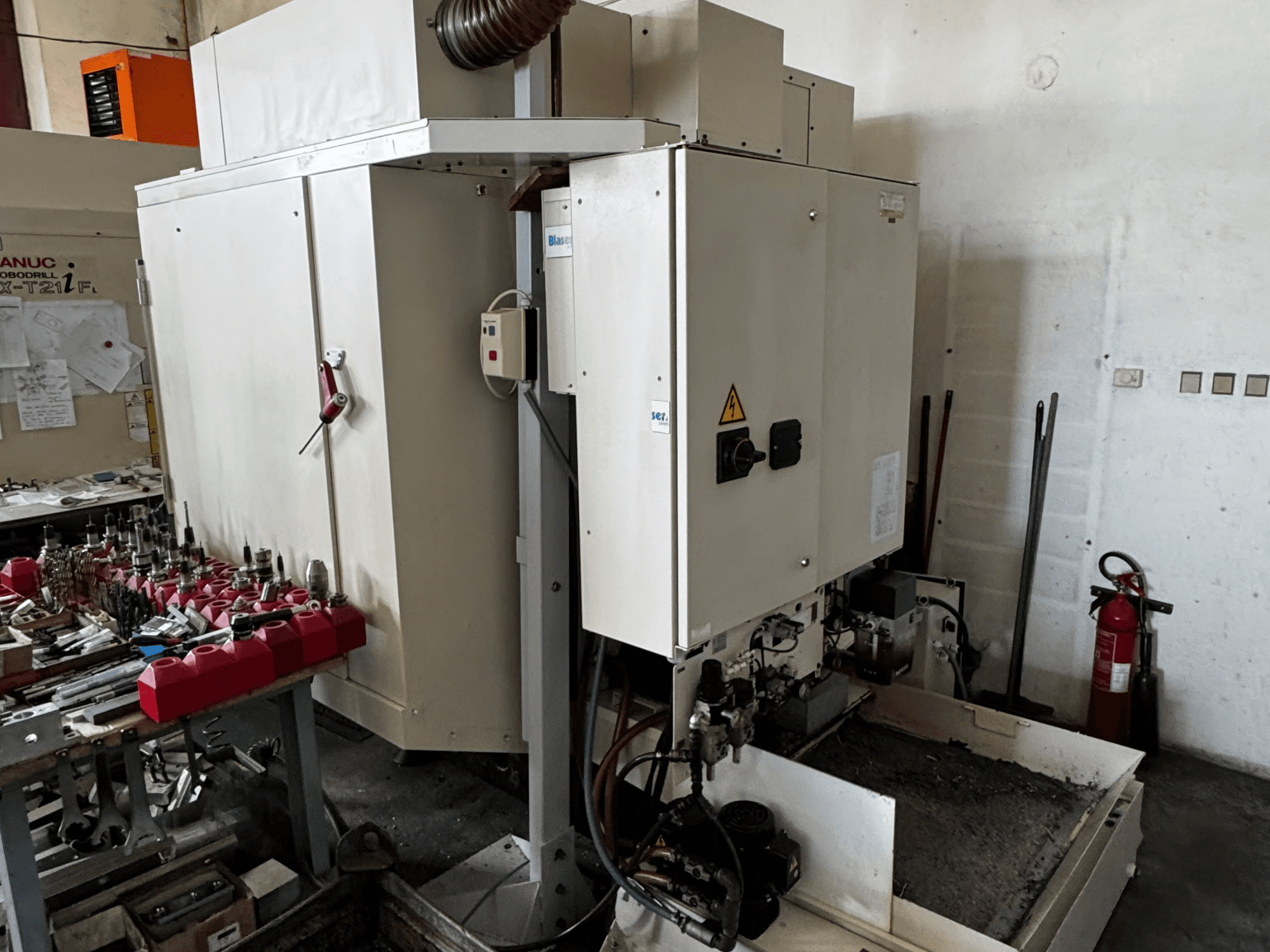 FANUC Robodrill alpha-T21iFL dikey işleme merkezi, kontrol panelini, takımları ve çalışma alanını gösteren yandan görünüm.