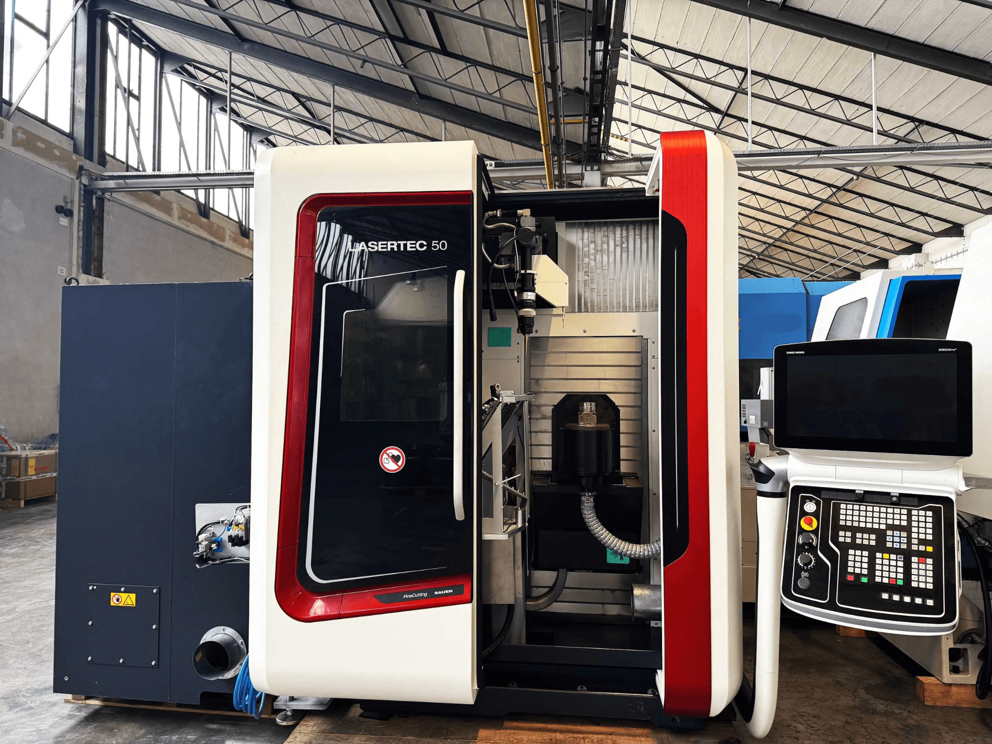 LaserTec 50 CNC makinesinin yandan görünümü, siyah beyaz kontrol paneli, görünür takım tutucusu ve endüstriyel ayarı.