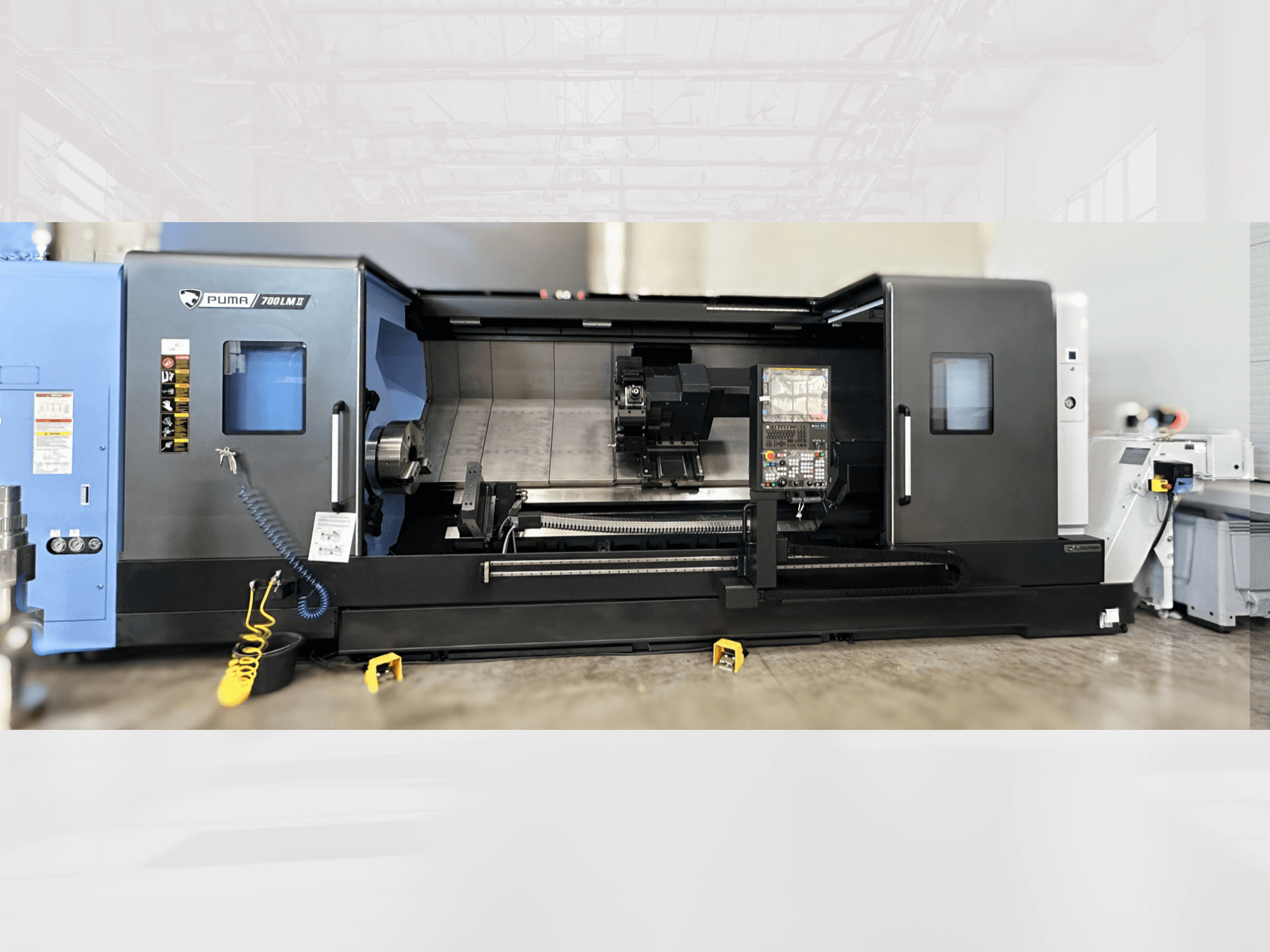 DN SOLUTIONS PUMA 700LM Torna-Freze Merkezi, önden görünüm, kontrol paneli ve görünür takımlarla işleme alanı.
