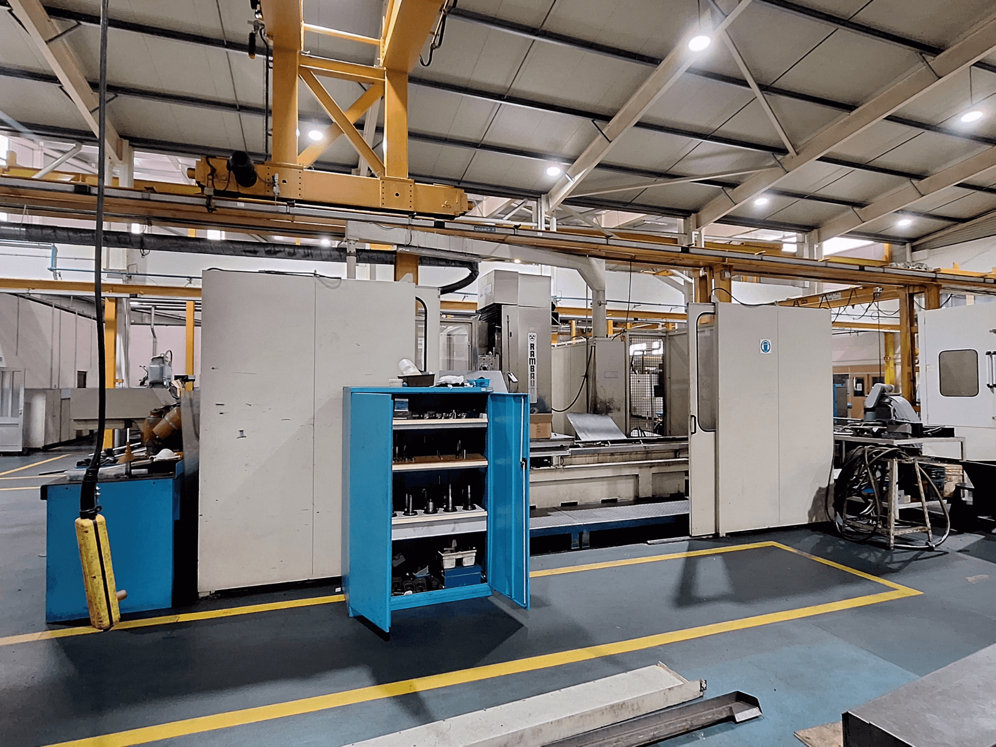 Portal freze makinesi Rambaudi RX 1250, geniş bir endüstriyel çalışma alanında takım deposu ile önden görünüm.