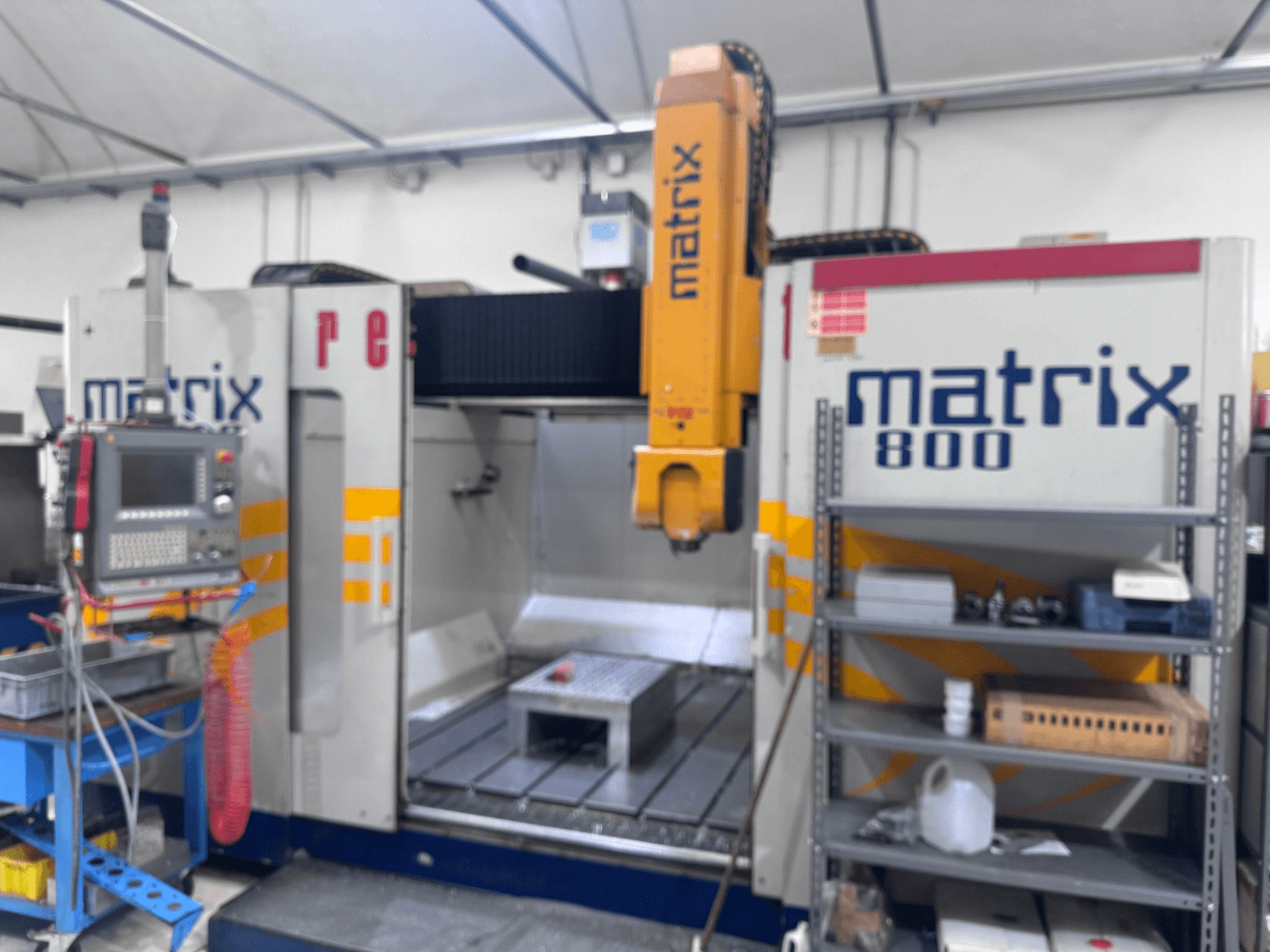 Atölye görünümünde Matrix 800 CNC makinesi, kontrol paneli, aletler ve çeşitli nesneler içeren çalışma masası.