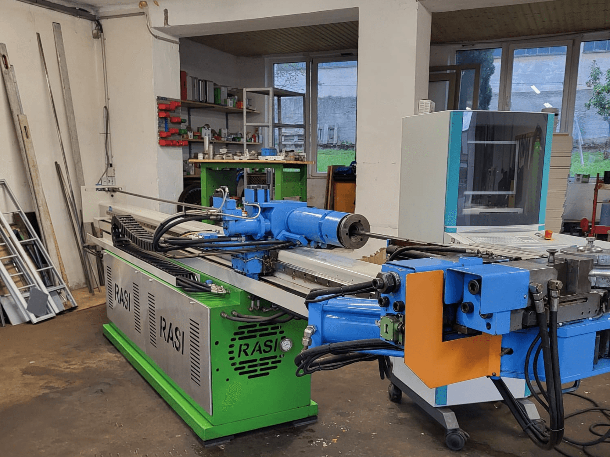 Atölye ortamında Rasi S 80.6 L G-V3C50 takım tezgahı, mavi ve yeşil bileşenleri ve kontrol panelini gösteren yandan görünüm.