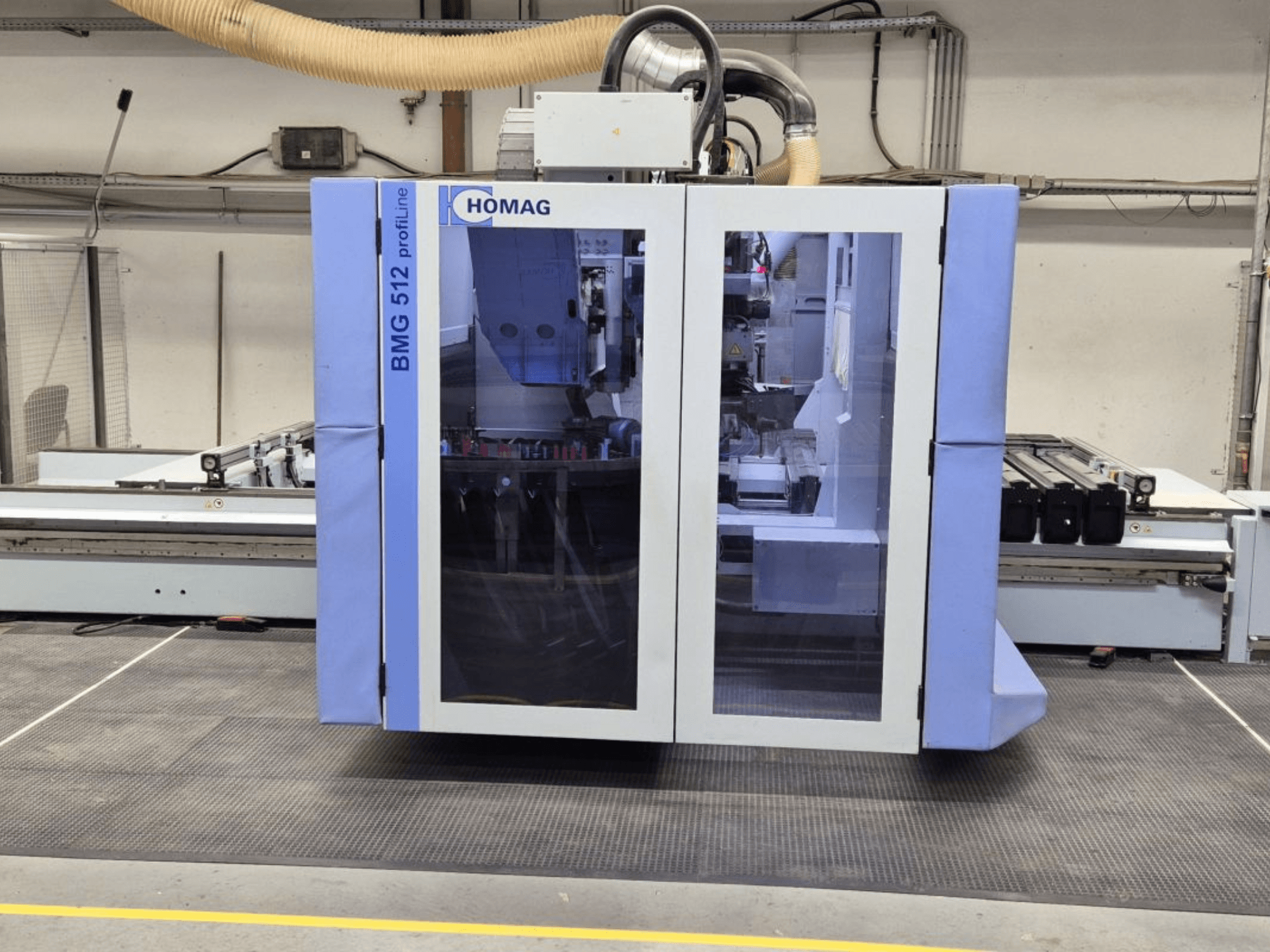 HOMAG BMG 512 ProfiLine CNC makinesi, önden görünüm, cam panel, görünür hassas aletler ve endüstriyel ortam.