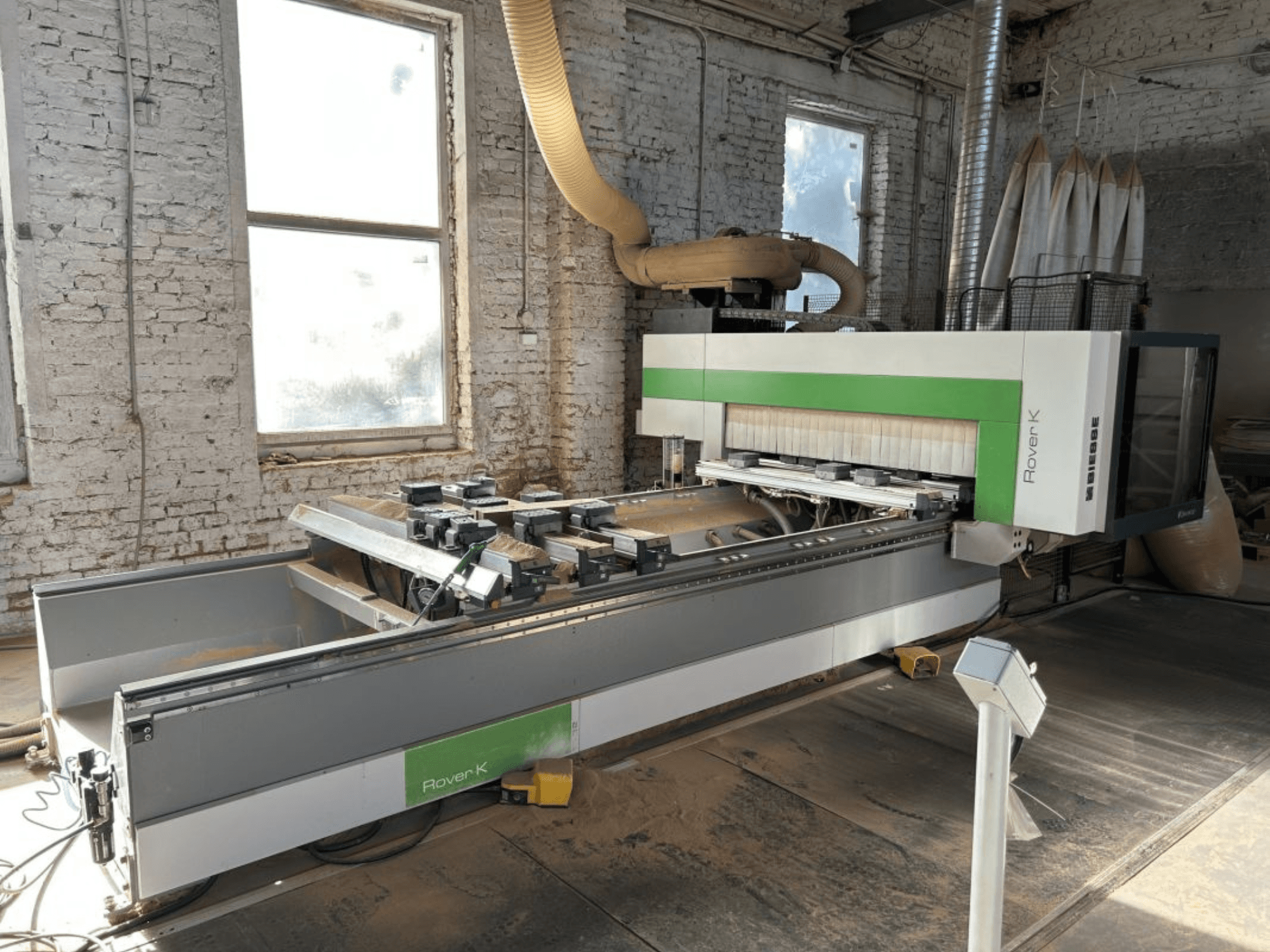 Bir atölyede bulunan BIESSE Rover K 1532 G CNC İşleme Merkezi, önden bakıldığında kesici aletleri ve çalışma yüzeyi görülüyor.