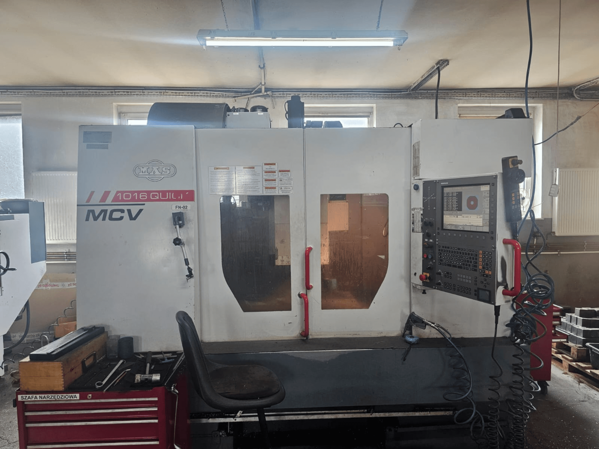 MVS MCV 1016 QUILL CNC makinesi, önden görünüm, kontrol paneli, takım çekmecesi ve takımların bulunduğu çalışma alanı.
