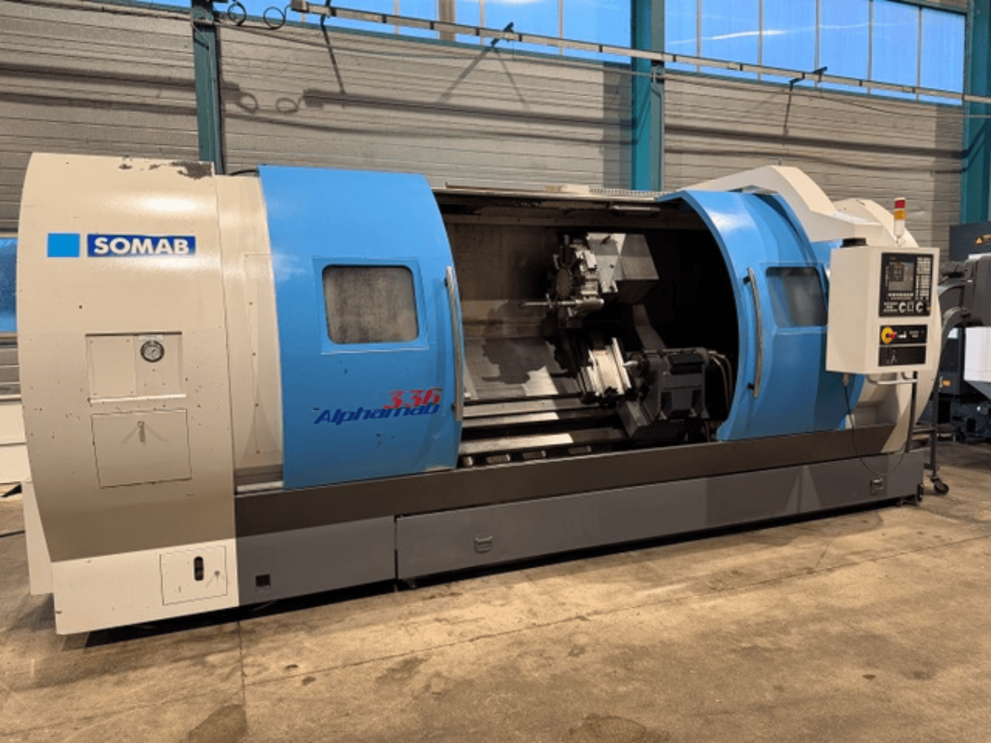SOMAB Alpha 336 CNC torna tezgahı, önden görünüm, mavi ve gri gövde ve yan tarafta kullanım için bir kontrol paneli.