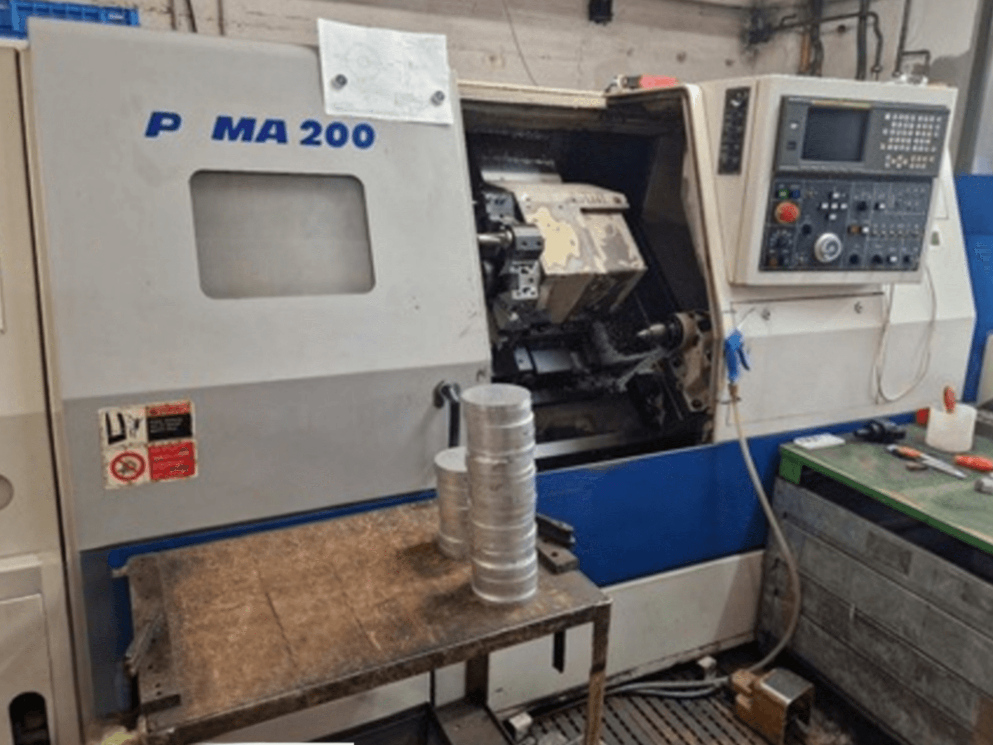 DAEWOO EcoTurn 200 yatay tornalama makinesi, önden görünüm, bir tabla üzerinde alüminyum iş parçaları, kontrol paneli görünür.