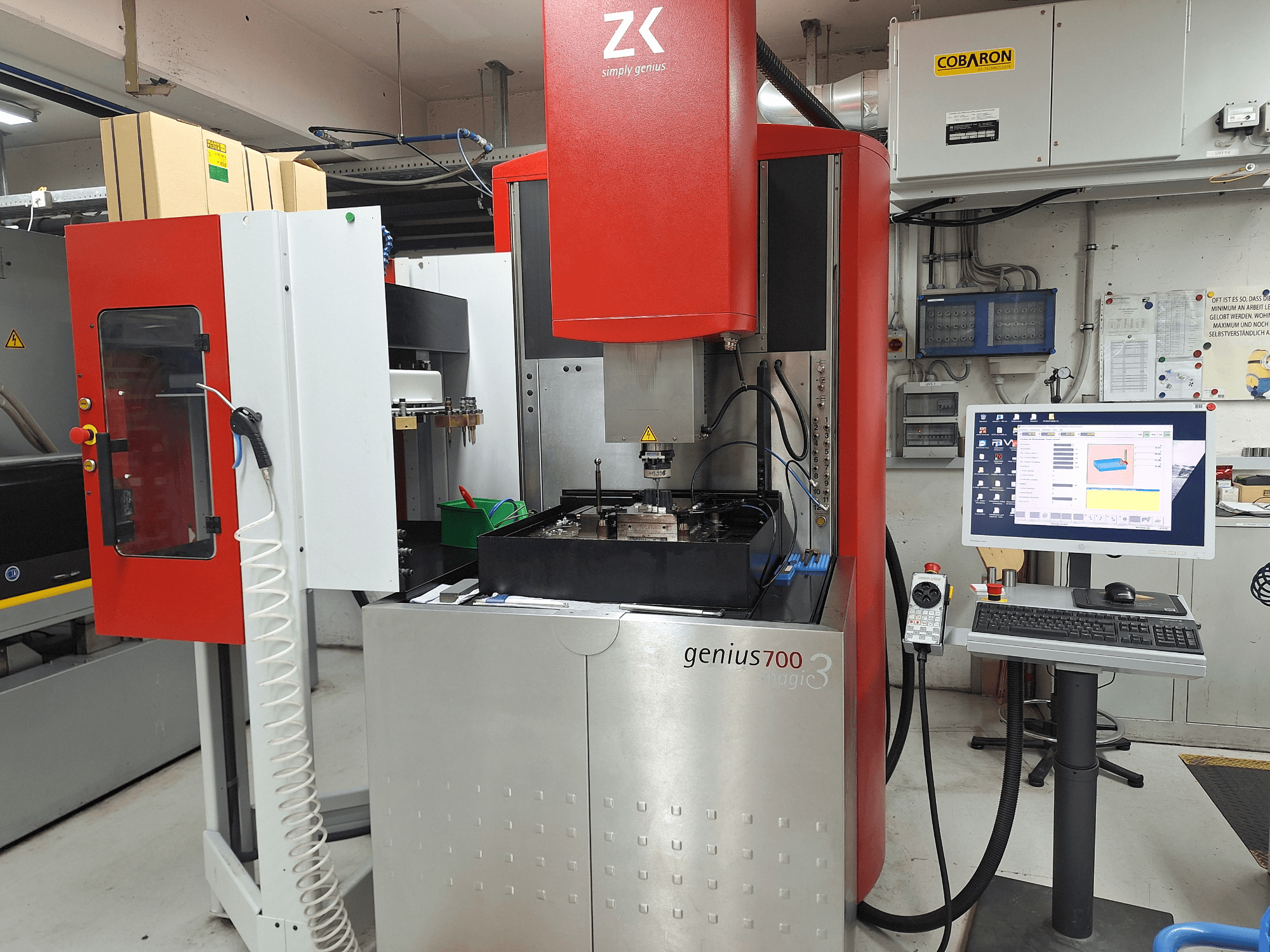 ZK'dan Genius 700 freze makinesi, önden görünüm, dokunmatik ekranlı kontrol paneli ve takım ve malzemelerle işleme alanına sahiptir.