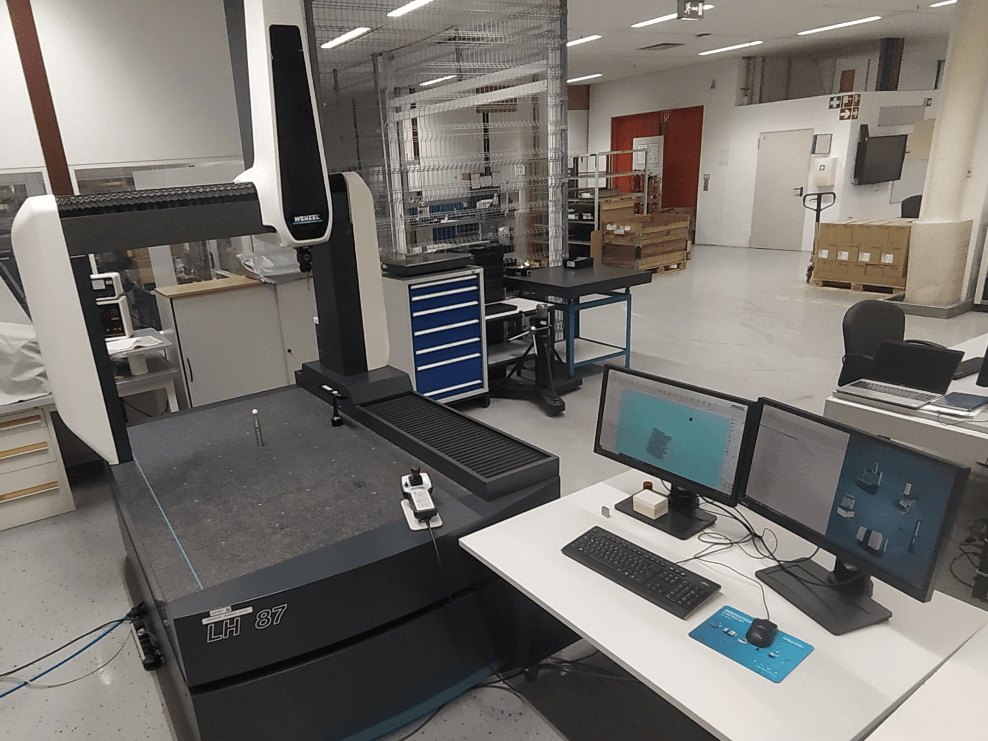Wenzel LH 87 koordinat ölçüm cihazı, çift monitör ve masa üzerinde ölçüm probu ile bir laboratuvar ortamında görülebilir.