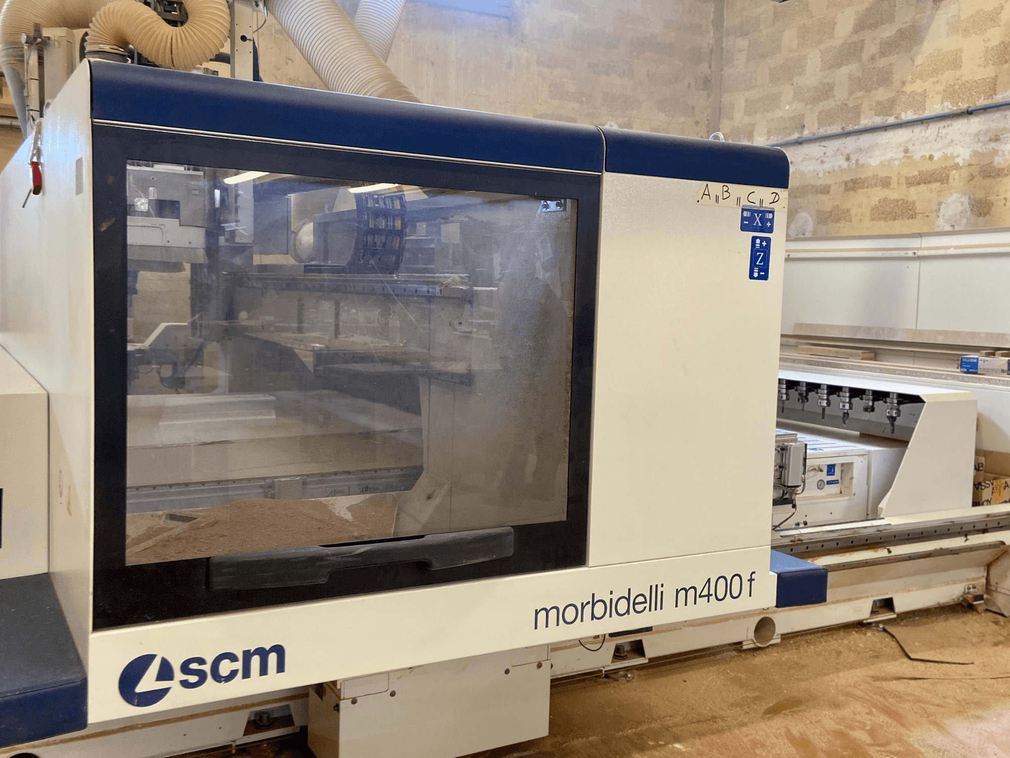 SCM Morbidelli M400F CNC makinesi, önden görünüm, bir kontrol paneli ve zeminde görünür talaş.