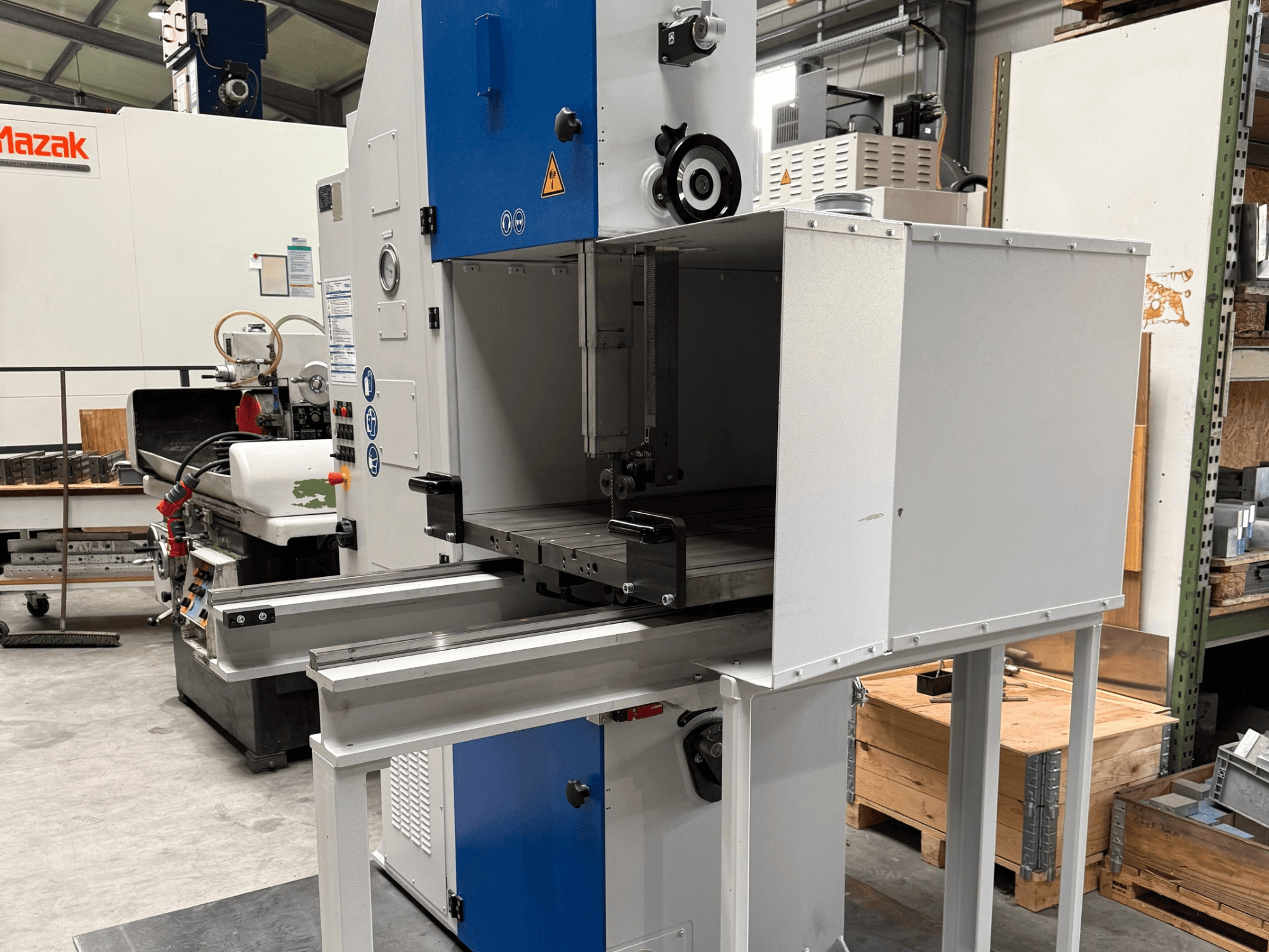 Mavi kontrol paneli, metal tabla ve güvenlik uyarıları ile önden görüntülenen Mazak endüstriyel makine.