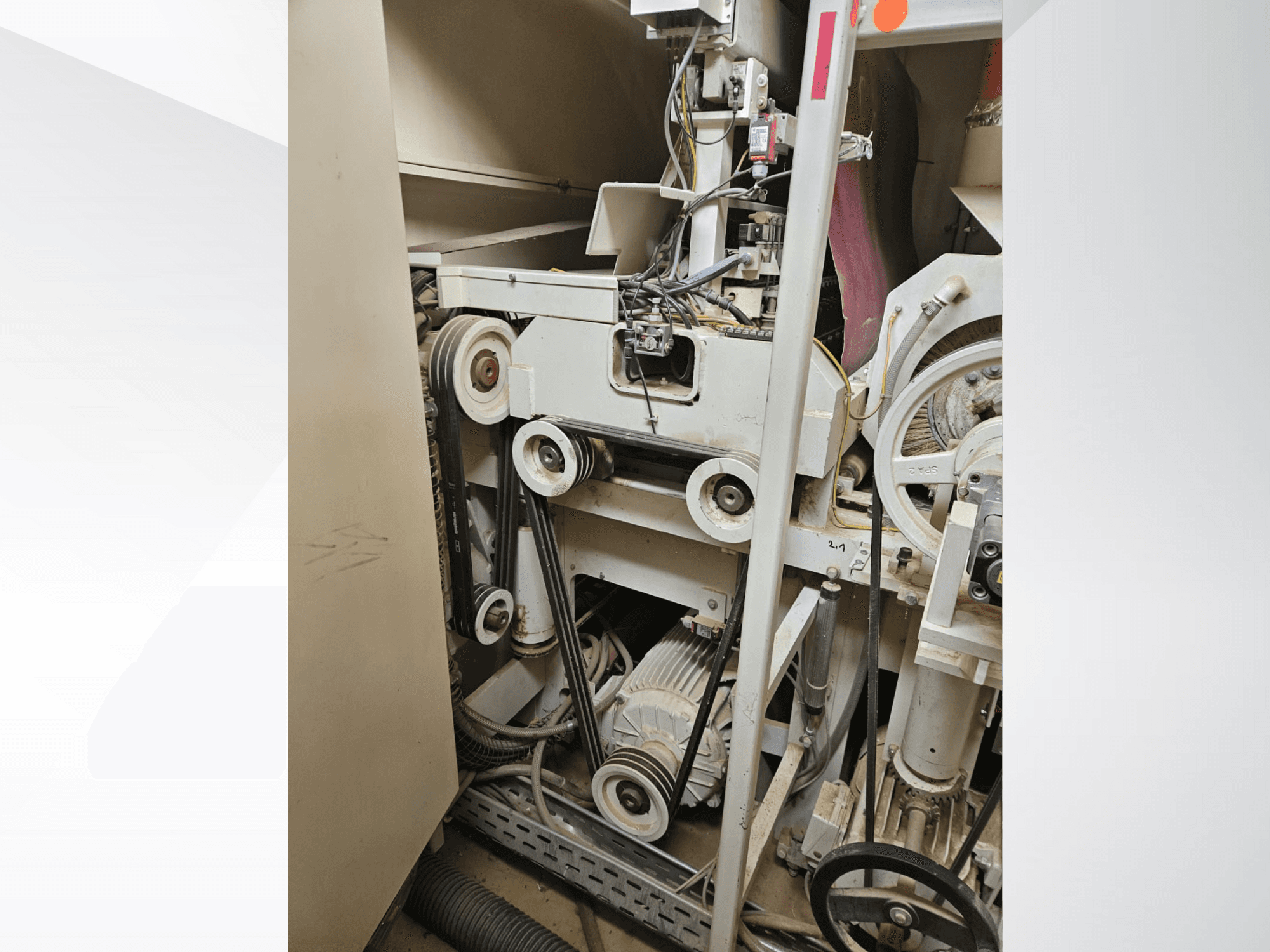 Motor ve kablo tesisatı içeren, kayış ve kasnaklı endüstriyel makine içi, yandan görünüm.