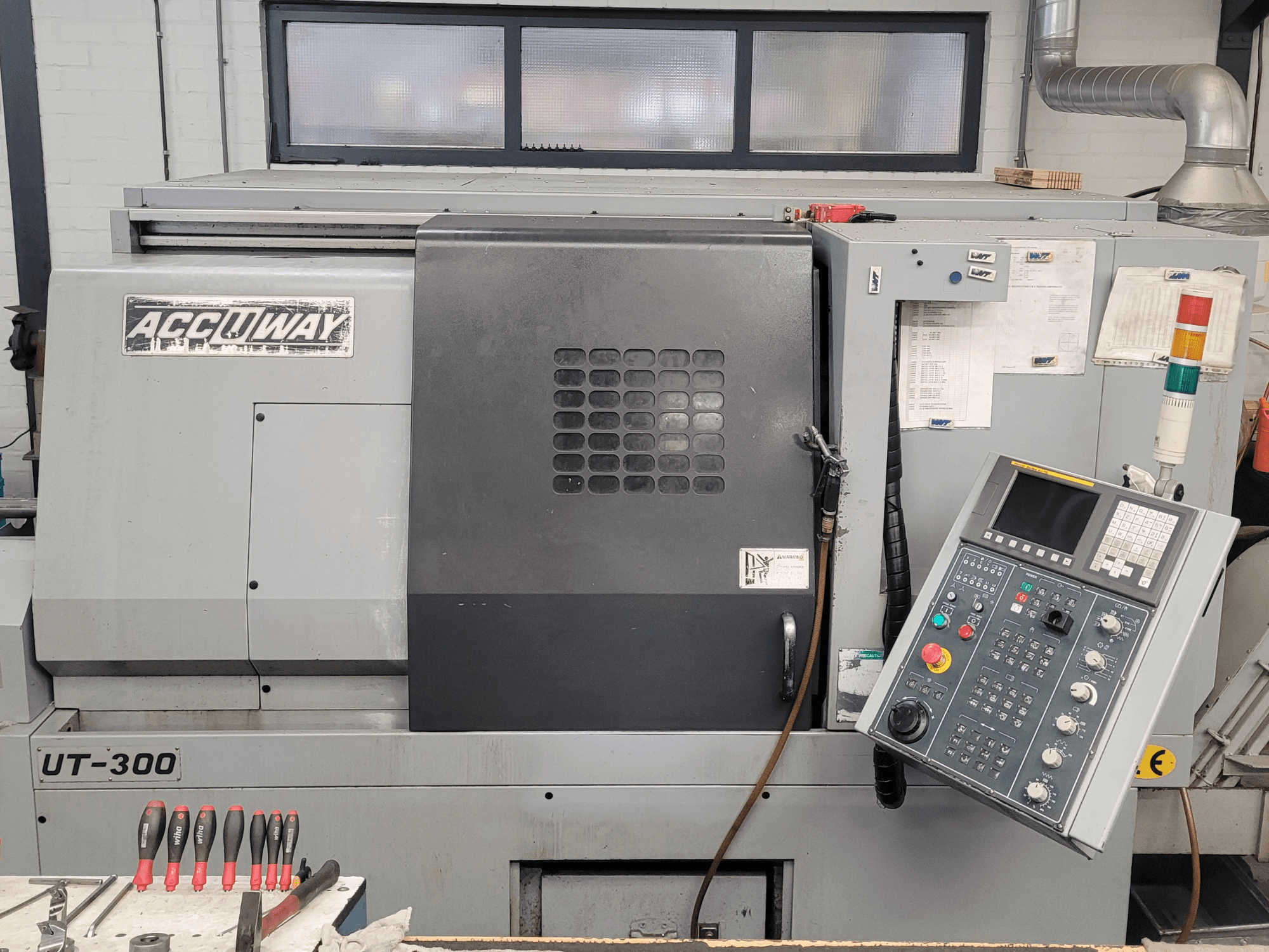 Accuway UT-300 CNC makinesinin önden görünümü, bir atölye ortamında kontrol paneli ve çeşitli çalışma düğmeleri.