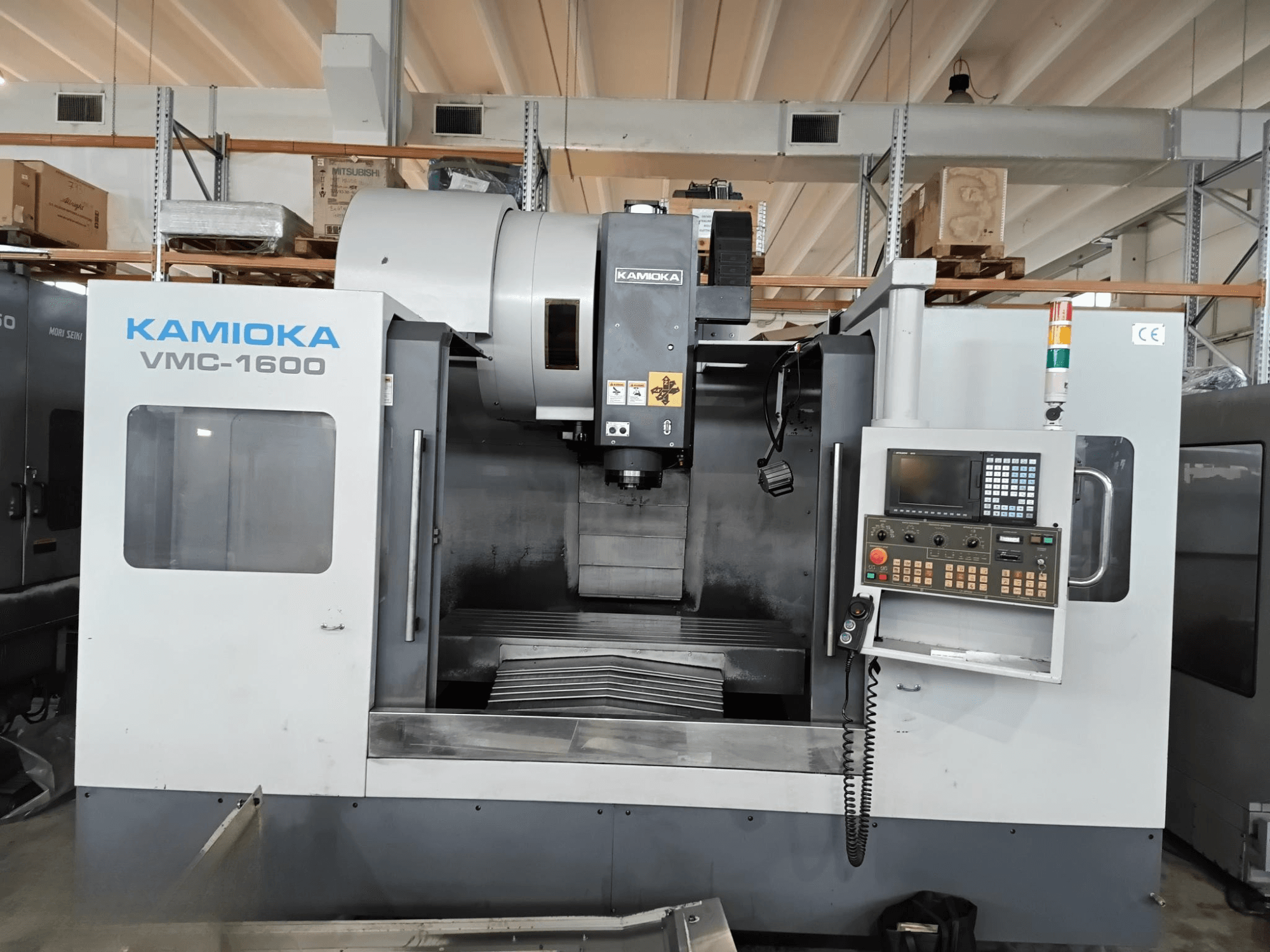 Fabrika ortamında Kamioka VMC-1600 dikey işleme merkezi, kontrol paneli ve görünür işleme yatağı ile önden görünüm.