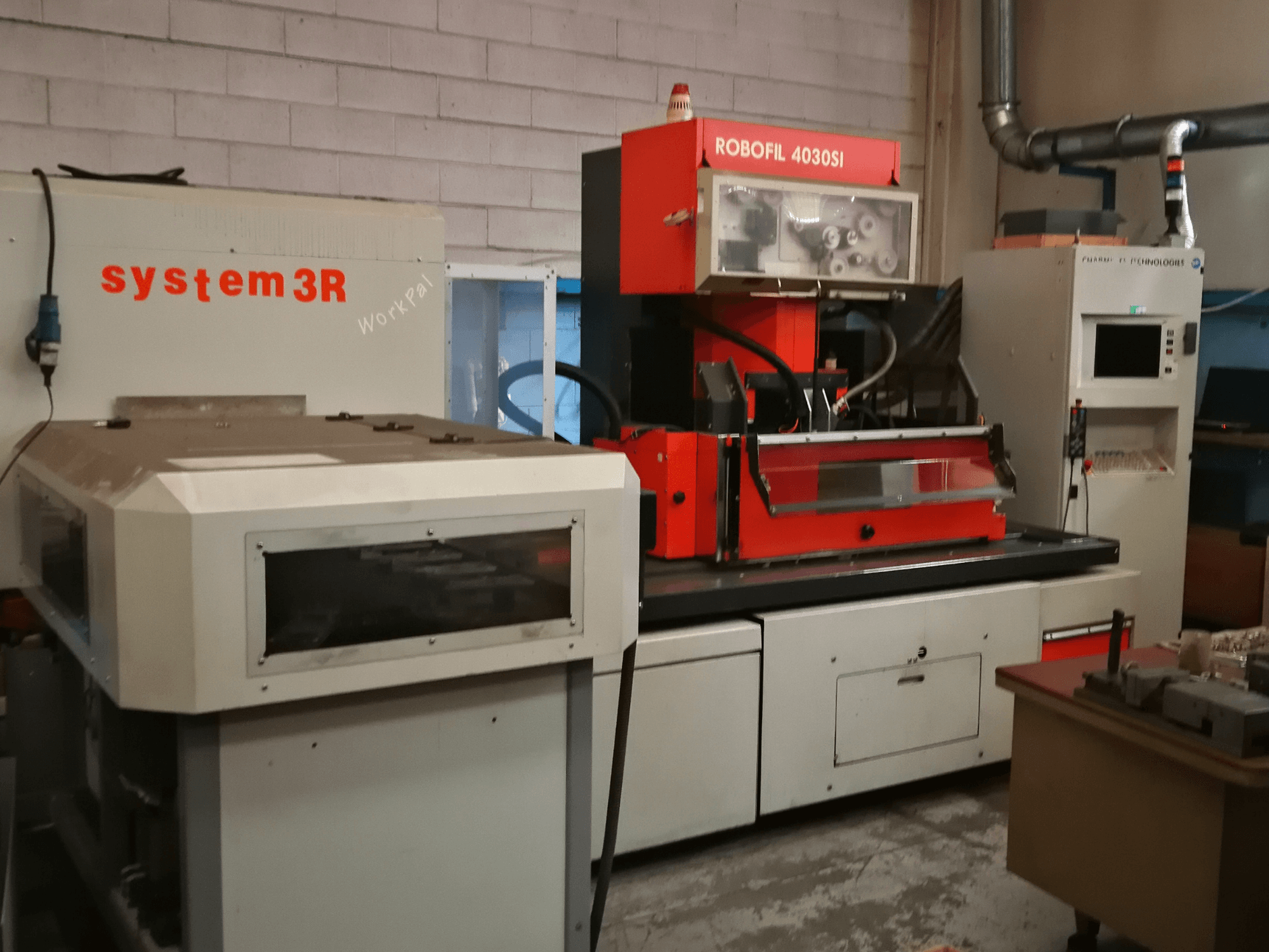 CHARMILLES ROBOFIL 4030 Si tel EDM makinesinin önden görünümü, kırmızı ve gri dış yüzey ve bitişik system3R iş istasyonu.