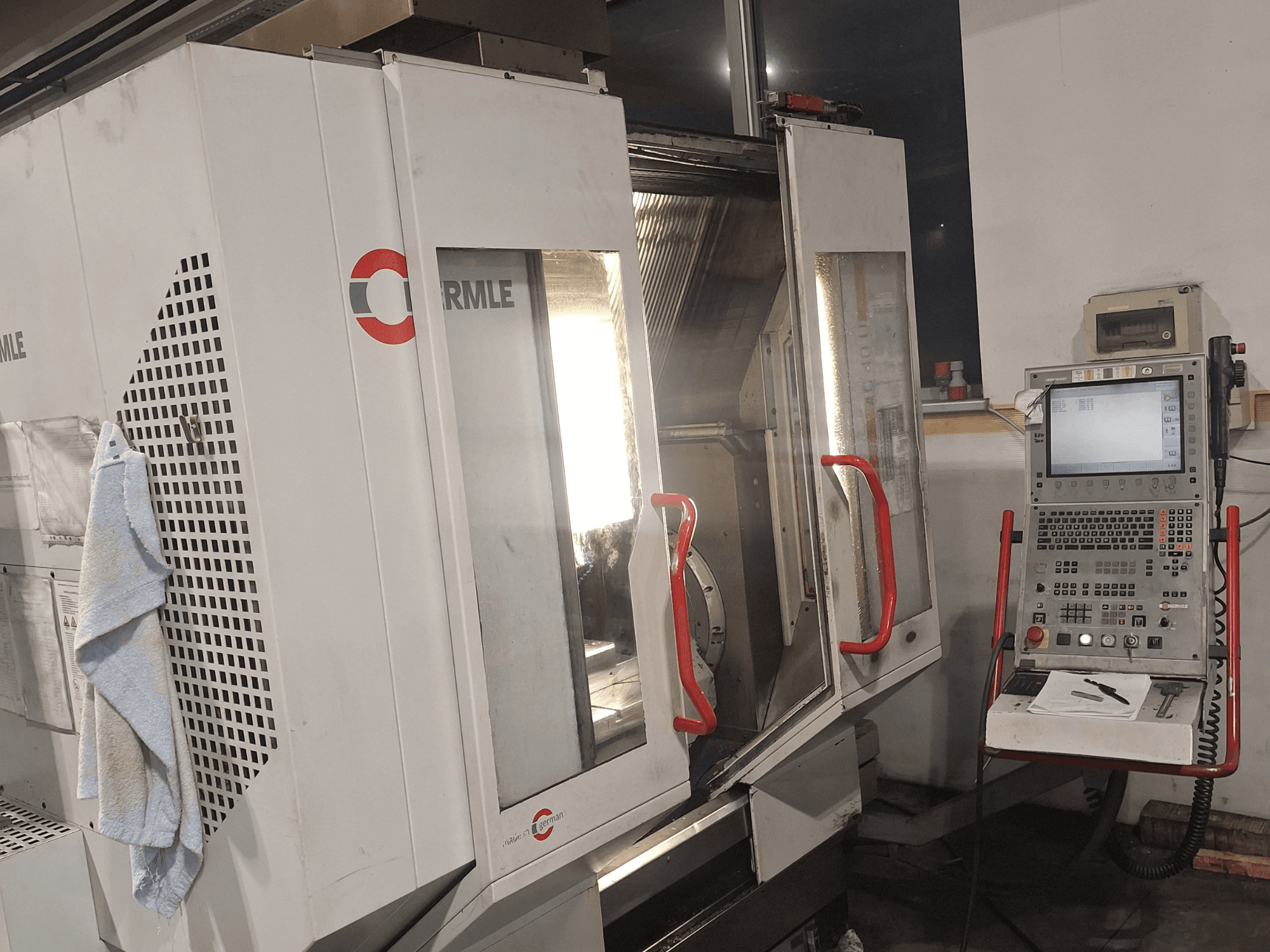 Cormile marka CNC makinesi, kısmen açık kapıları ve ekranlı ve düğmeli kontrol panelini gösteren önden görünüm.