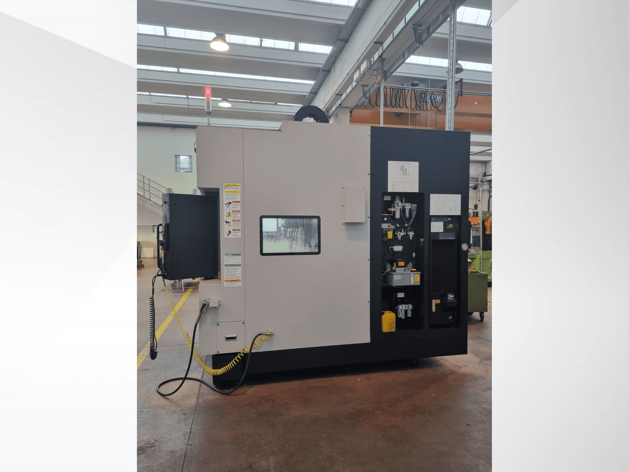 Yandan görünümlü endüstriyel makine, düğmeler, göstergeler ve güvenlik uyarı etiketi içeren bir kontrol paneline sahiptir.