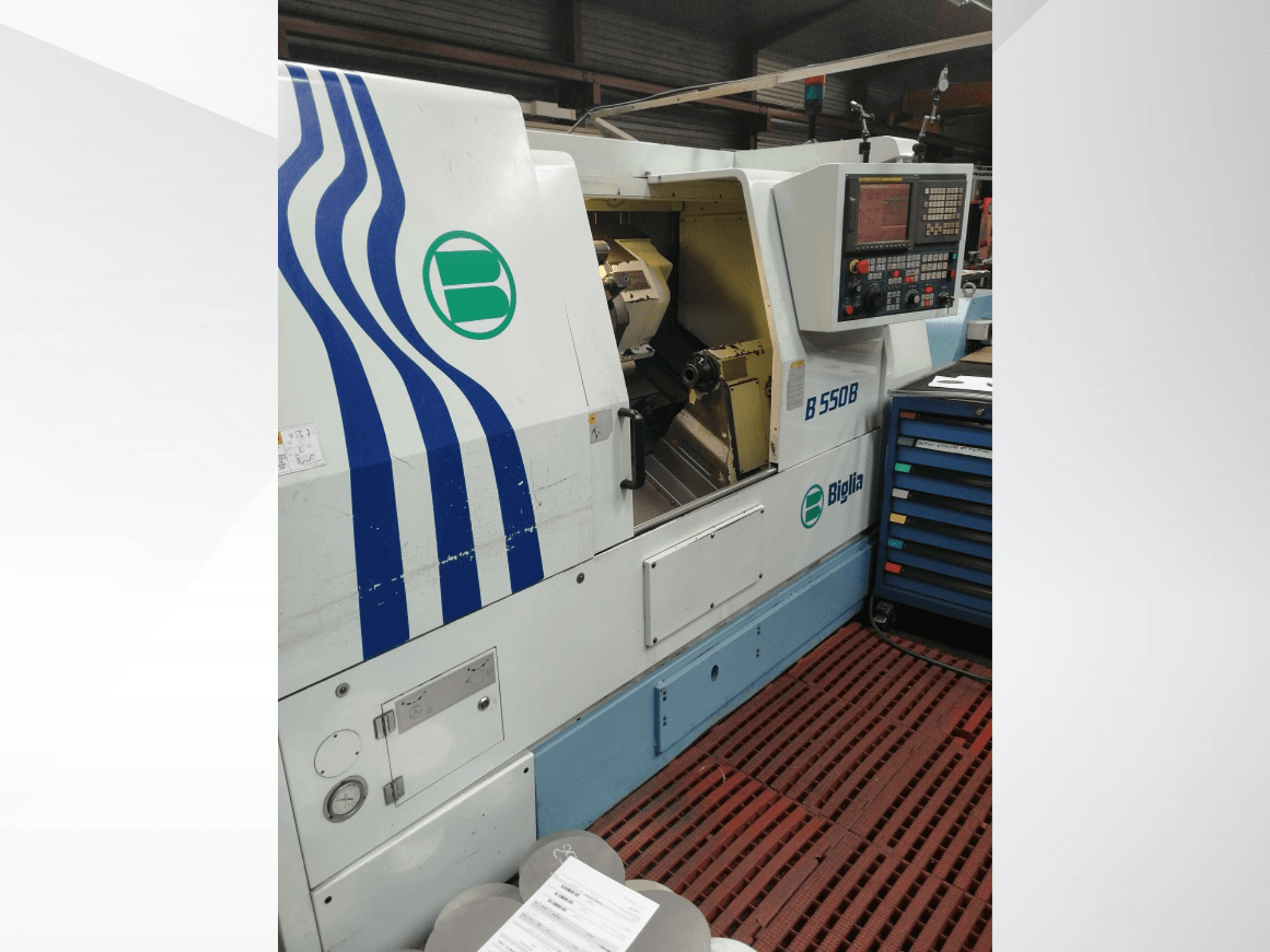 Biglia B 550 B CNC torna makinesi önden gösterilmiştir, kontrol paneli, metal işleme alanı ve renkli takım deposu bulunmaktadır.