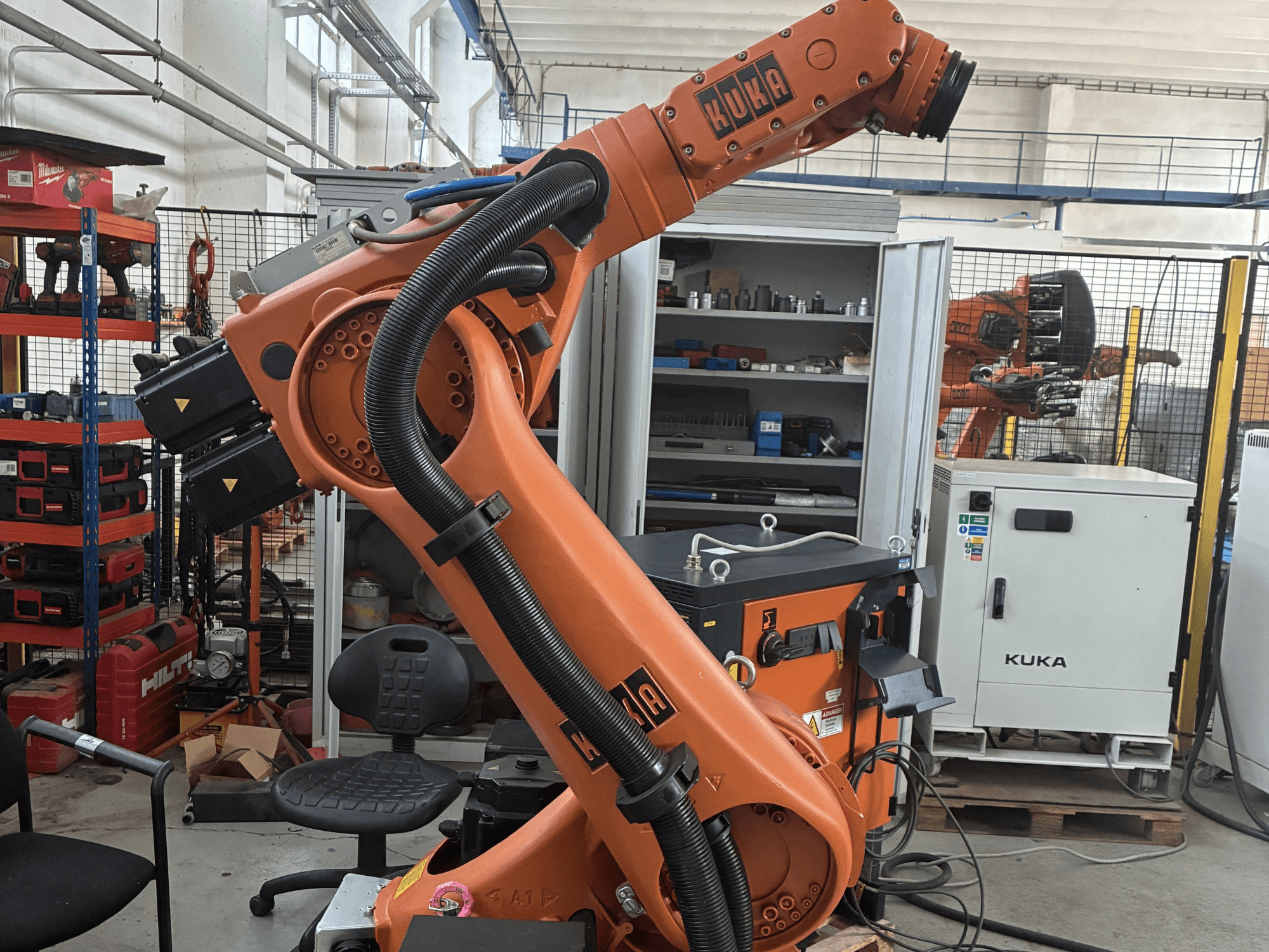 Endüstriyel bir ortamda KUKA KR30-3 robot kolu, kabloları ve kontrolleri gösteren yandan görünüm, arka planda aletler ve raflar.