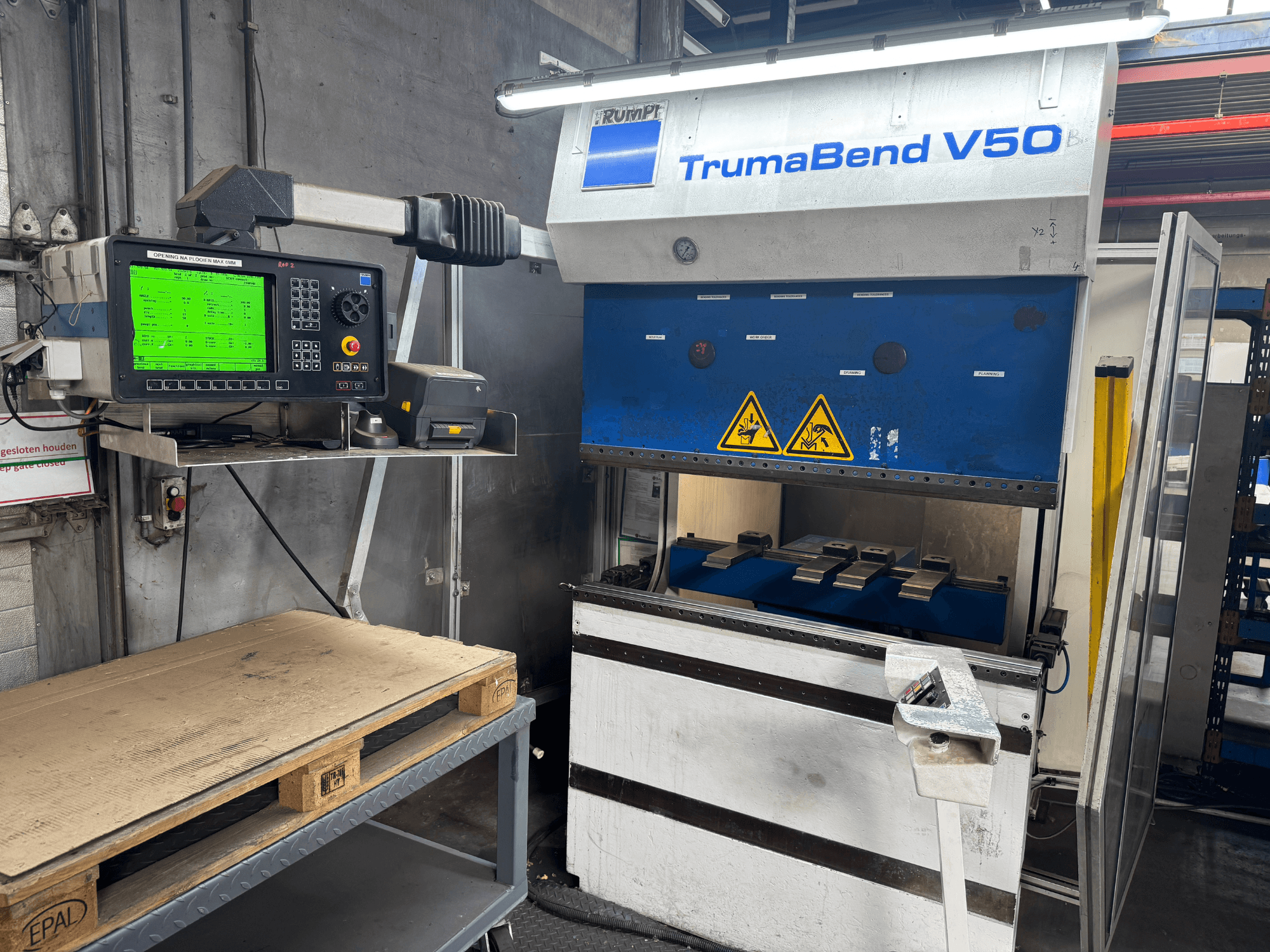 TRUMPF TrumaBend V50 abkant pres, önden görünüm, ayarların ve güvenlik uyarı işaretlerinin gösterildiği kumanda paneli.