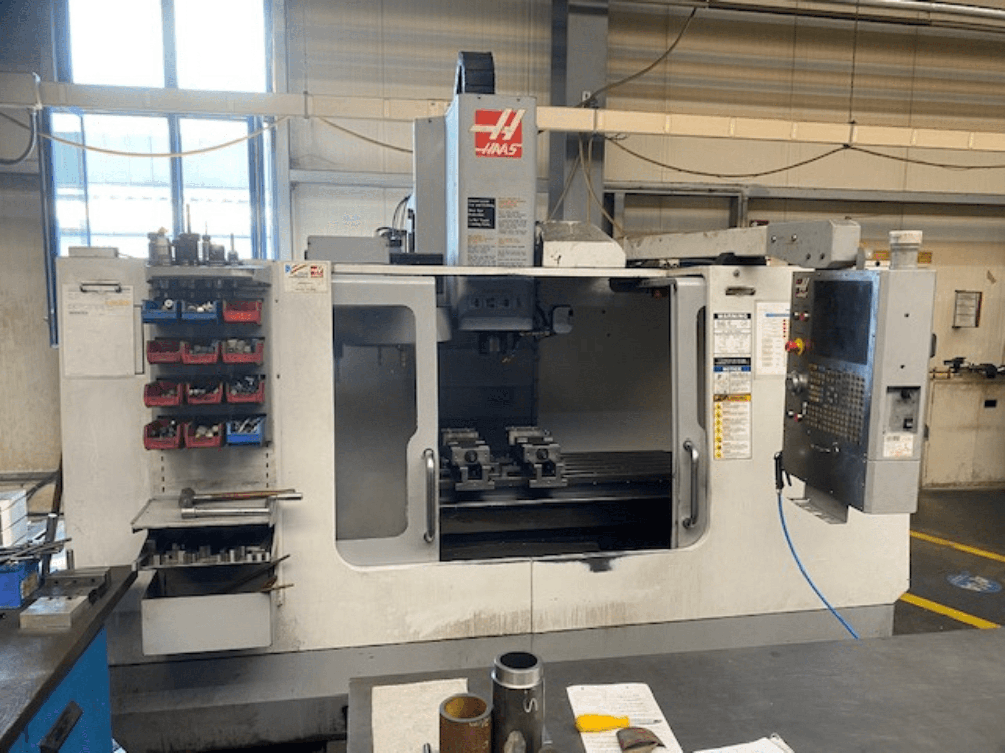 Haas CNC freze makinesinin önden görünümü, model VF-2, takım deposu, kontrol paneli ve çalışma alanı takımları görünür.