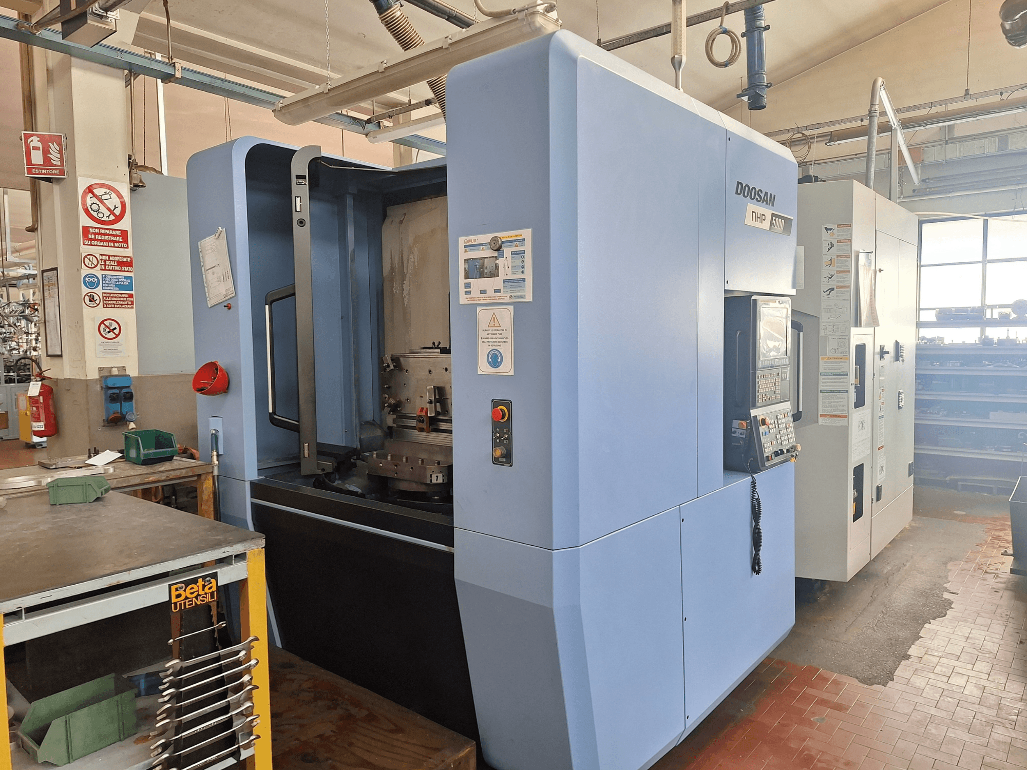 DOOSAN NHP 5000 Yatay İşleme Merkezi bir atölyede, kontrol panelini ve işleme alanını gösteren yandan görünüm.