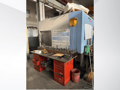 Kırmızı tezgahlı ve depolu, alet ve ekipman sergileyen Doosan işleme merkezi, önden görünüm.