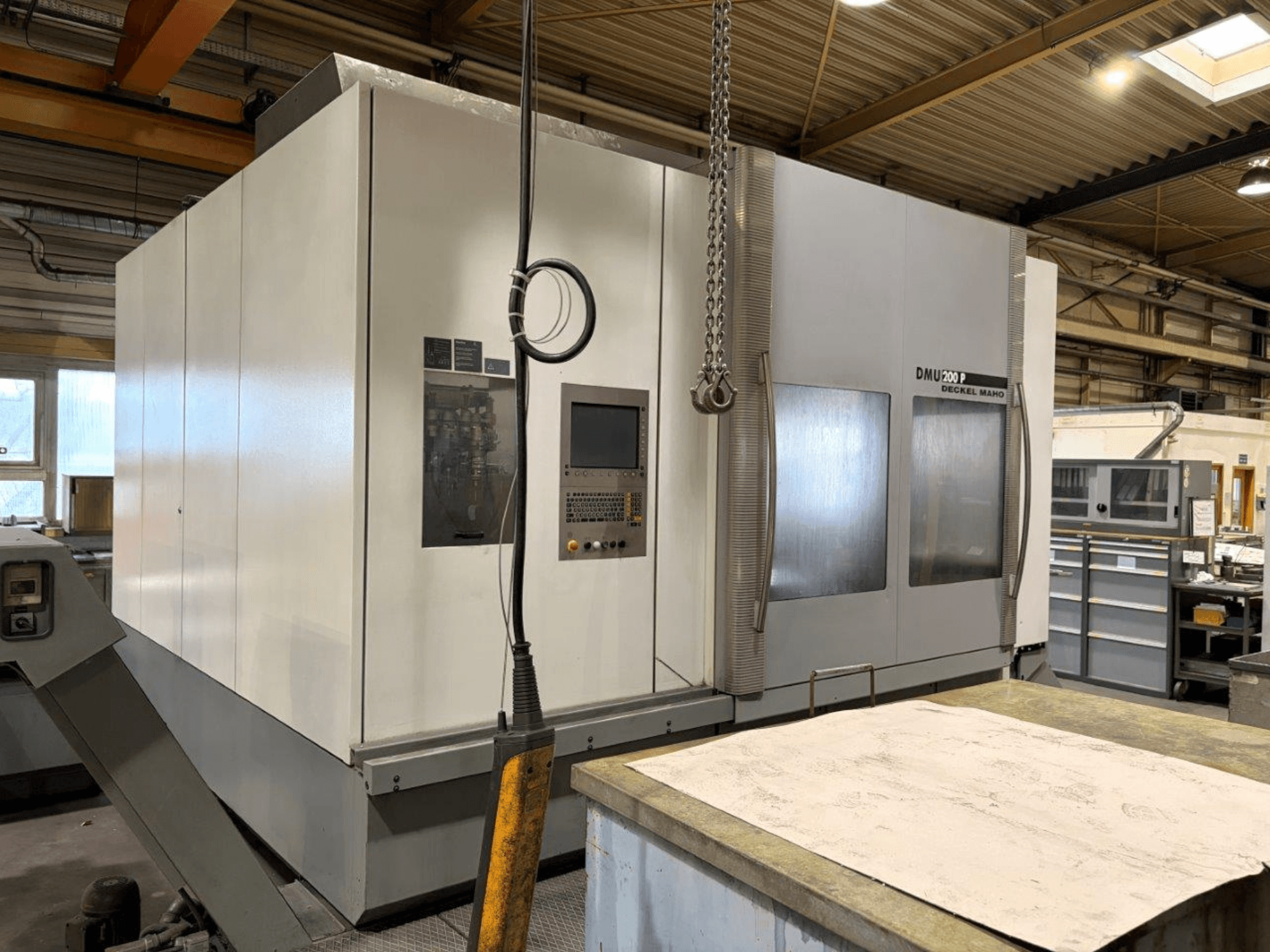 DMG MORI DMU 200 üniversal işleme merkezi bir atölyede, önden görünüm, kontrol paneli ve dış özellikleri sergileniyor.