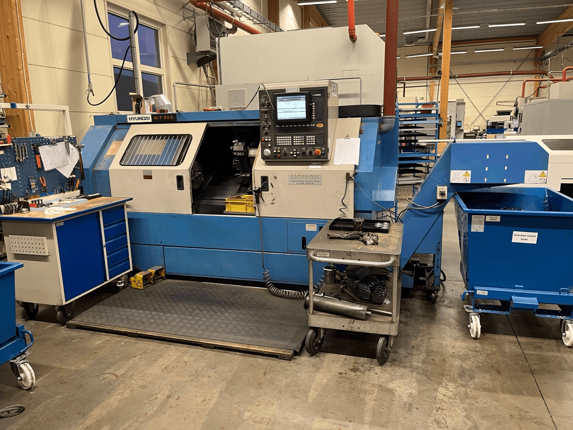 Hyundai HIT 30S yatay tornalama makinesi, önden görünüm, kontrol paneli ve atölye ortamında yakındaki bir arabada bulunan aletler.