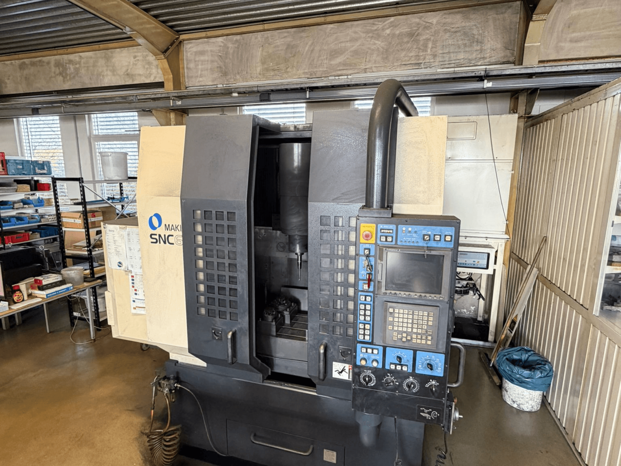 Makino SNC 64-A15 dikey işleme merkezinin önden görünümü, kontrol paneli, işleme alanı ve endüstriyel çalışma alanı.