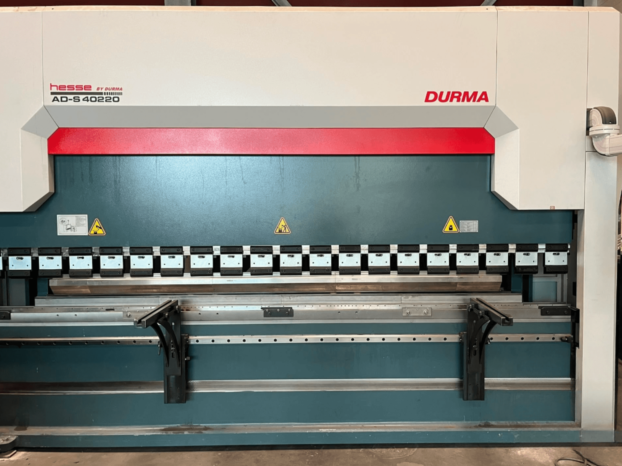 Durma AD-S 40220 pres freninin önden görünümü; çok sayıda bükme aletine ve güvenlik etiketlerine sahiptir.