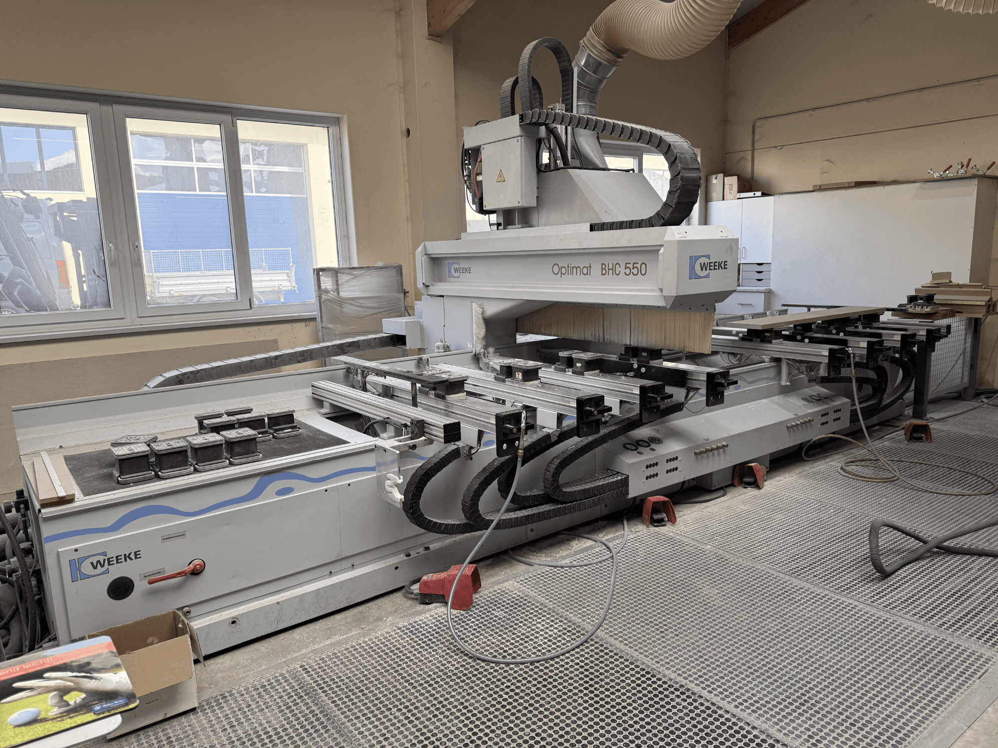 CNC Ahşap İşleme Merkezi Weeke Optimat BHC 550, takım kafasını ve çalışma tezgahını gösteren önden görünüm, toz emme sistemi görünür.