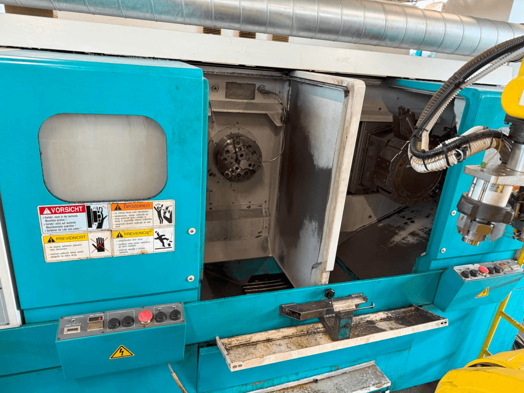 DOOSAN H310T yatay torna makinesi, kontrol panelini ve iş mili alanını gösteren önden görünüm ve güvenlik uyarıları.