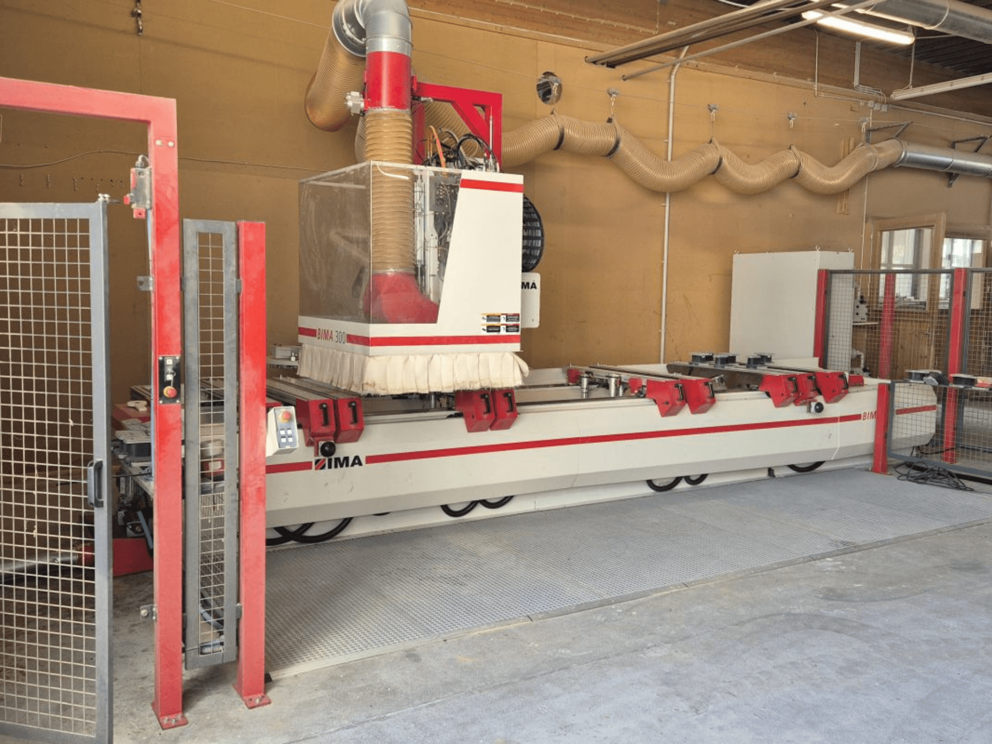 Atölyede CNC İşleme Merkezi IMA BIMA/300/125/530, kırmızı vurgular ve güvenlik muhafazası ile önden görünüm.