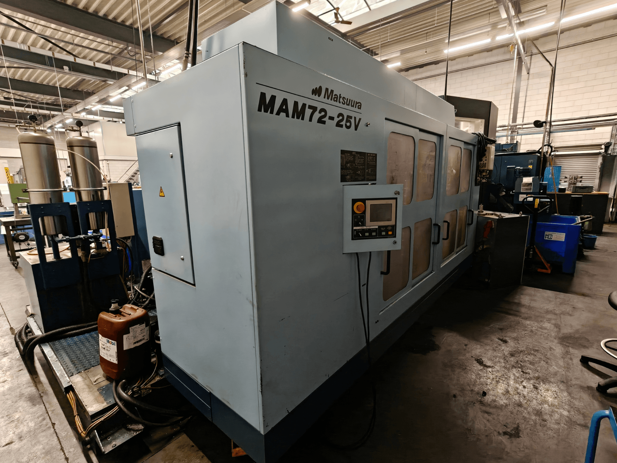 Matsuura MAM72-25V CNC makinesi, yandan görünüm, kontrol paneli, çift soğutma sıvısı tankı ve endüstriyel bir ortamda çalışma alanı özellikleri.