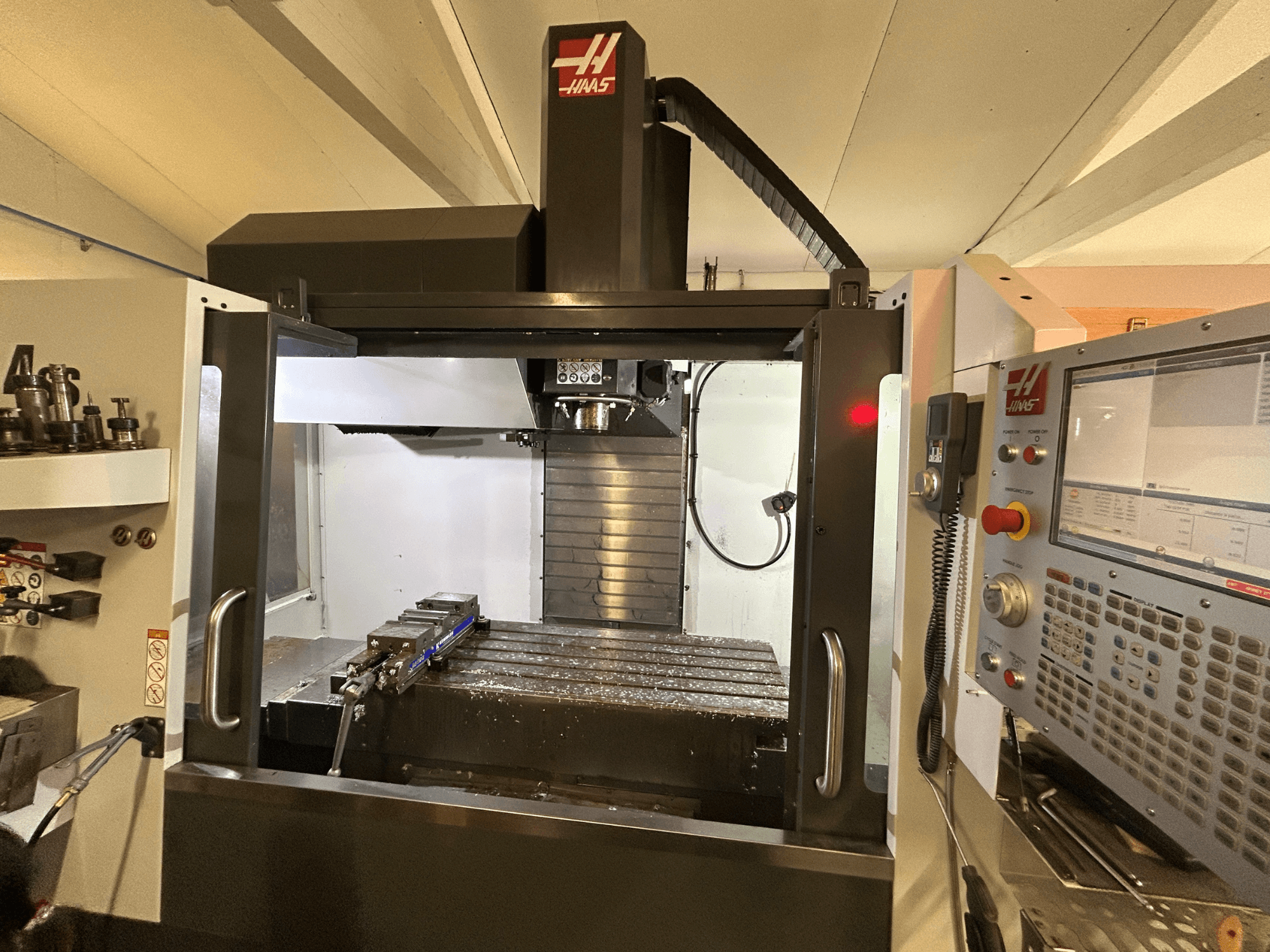 HAAS VF-4SS dikey işleme merkezi, önden görünüm, kontrol paneli, takım tutucu ve metal talaşı ile çalışma alanı.